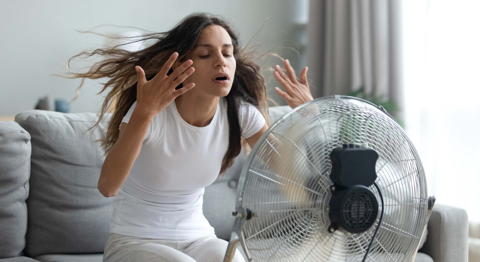 Mujer con mucho calor delante de un ventilador