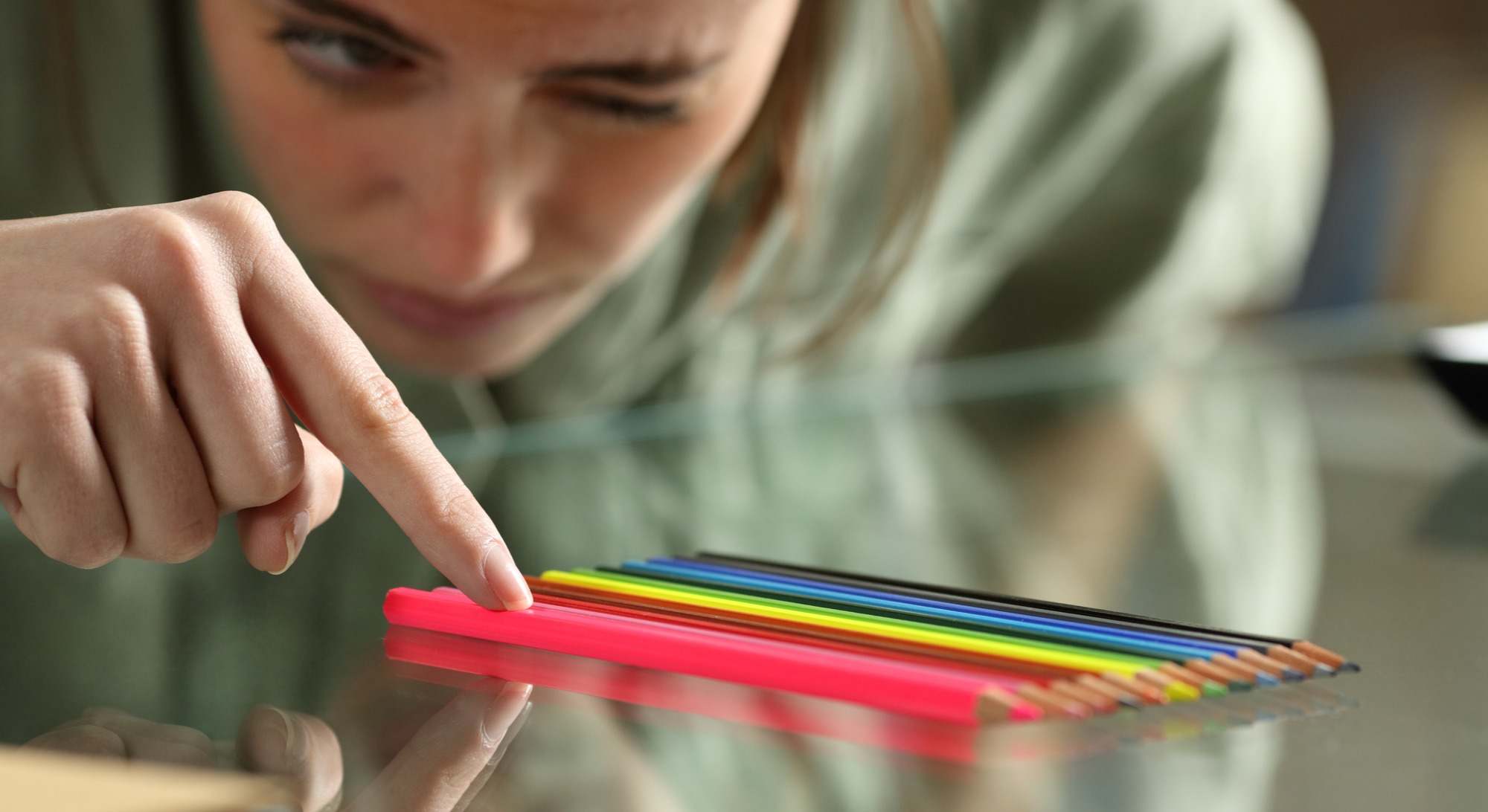 Mujer colocando perfectamente unos lápices de colores en una mesa
