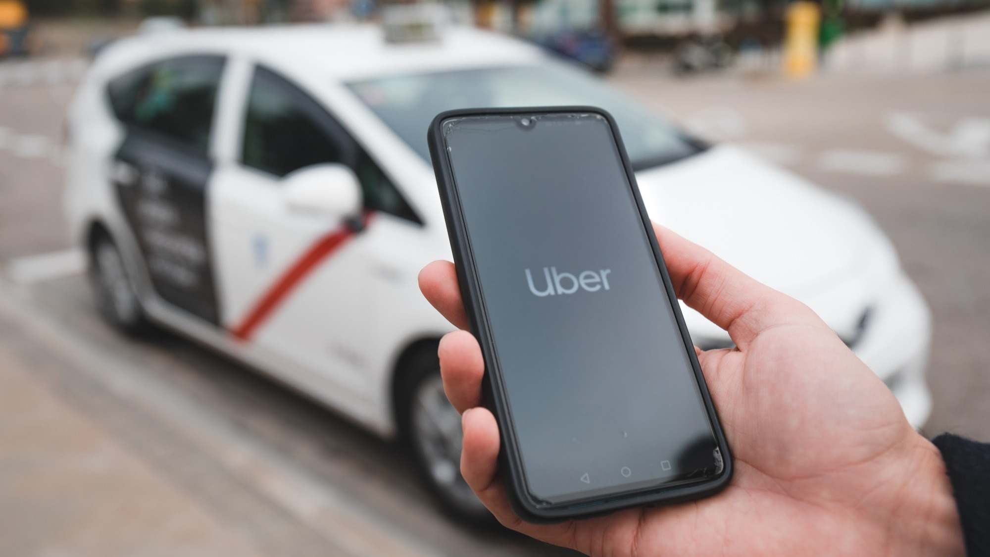 Persona esperando un Uber con un taxi al fondo.