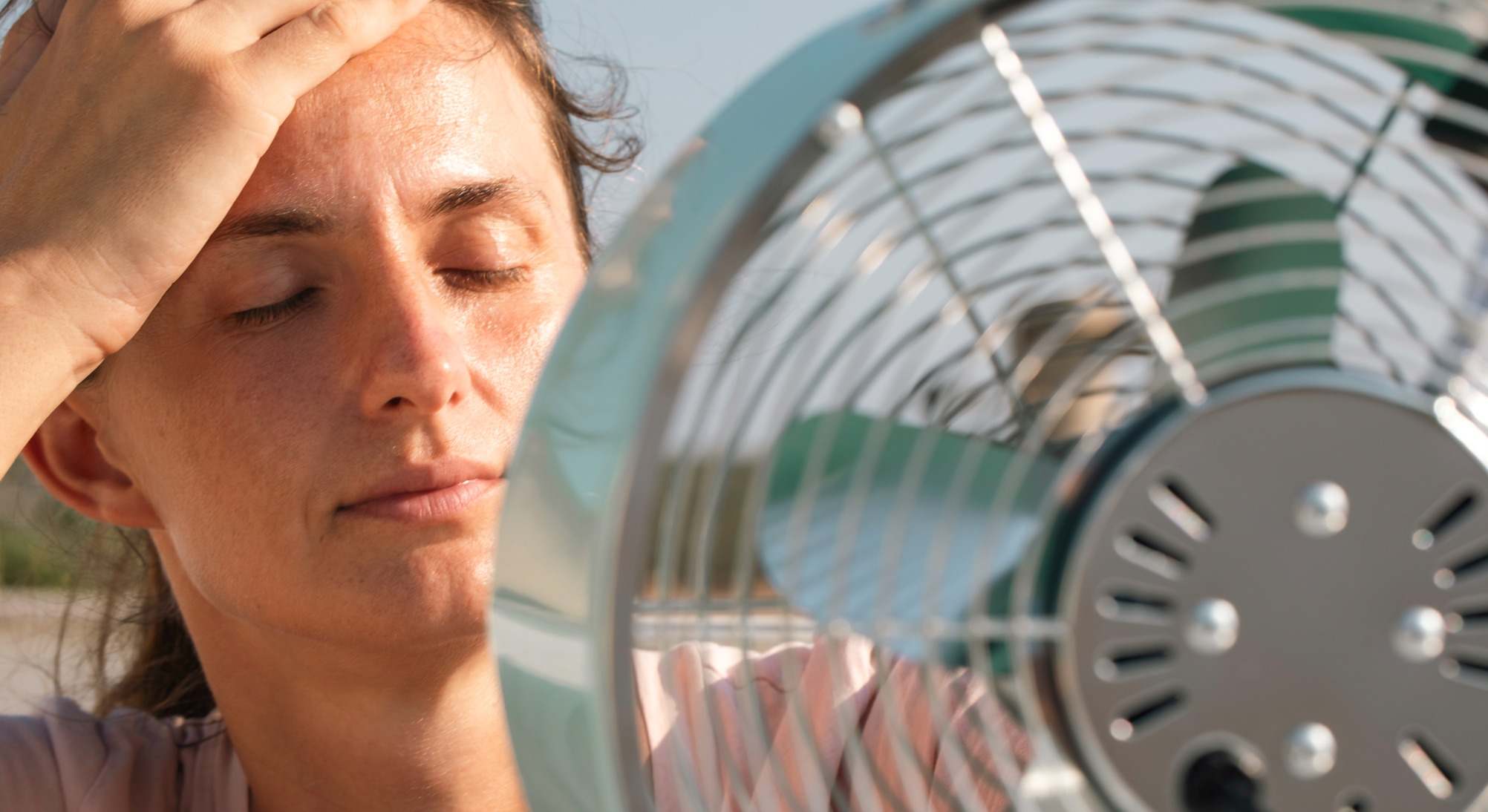 Mujer con mucho calor delante de un ventilador
