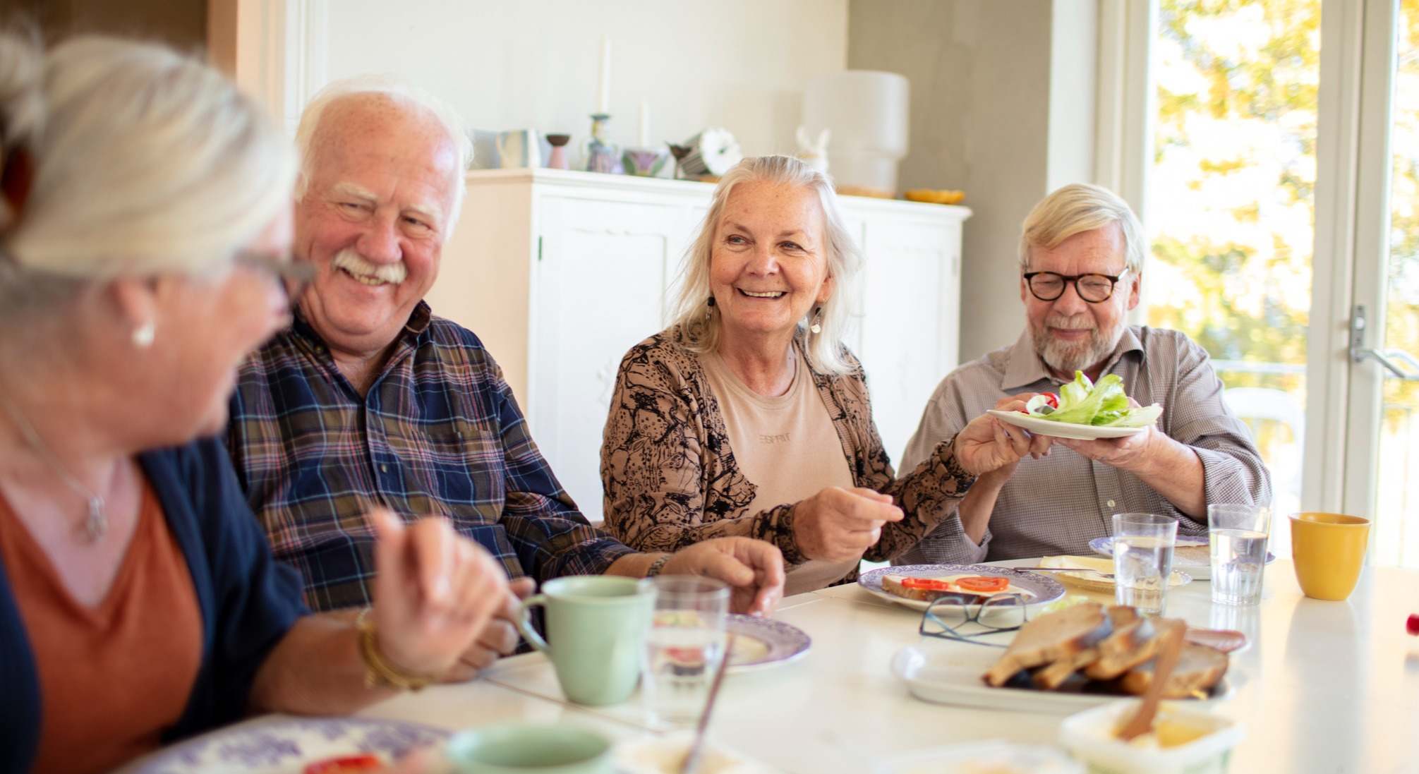 Un grupo de cuatro personas mayores desayunando felices