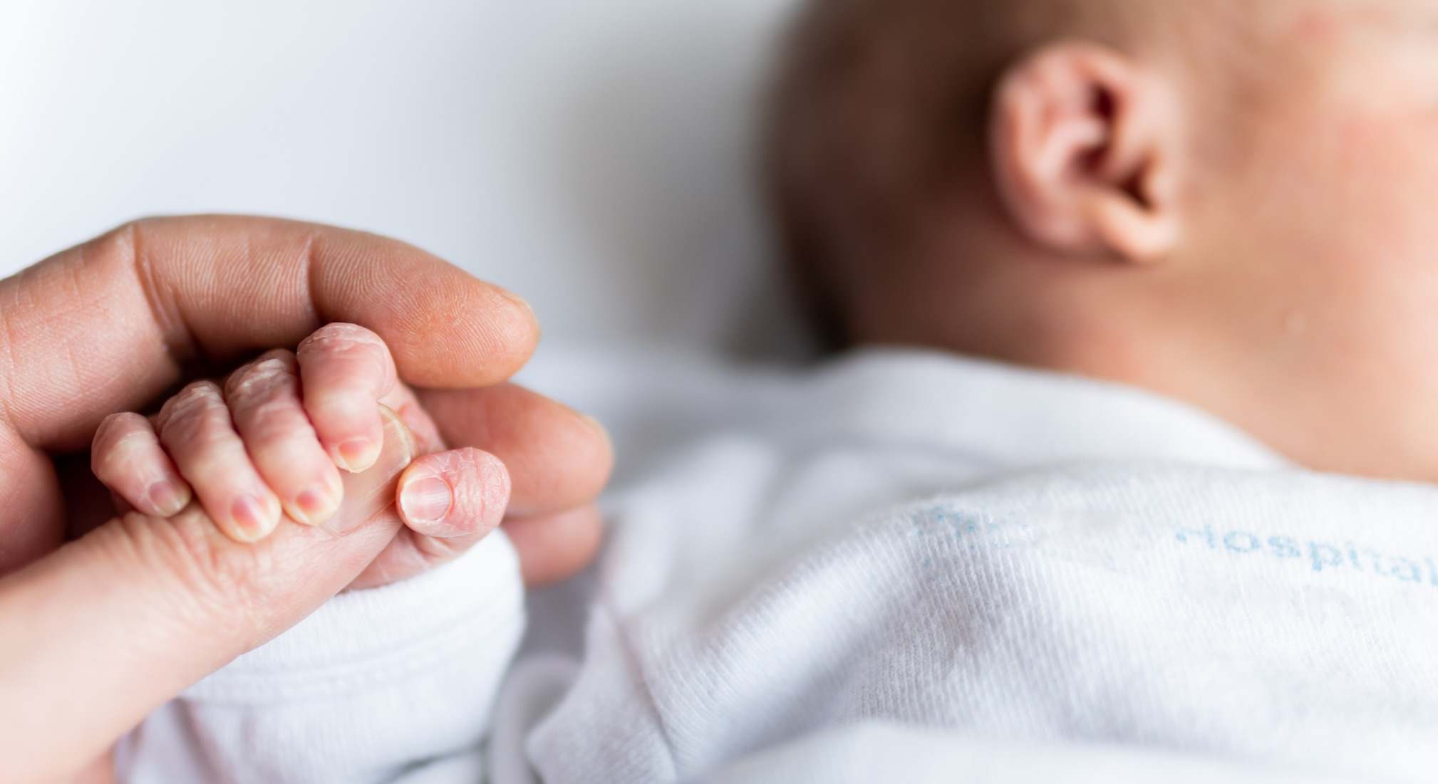 Bebé recién nacido de la mano de su madre