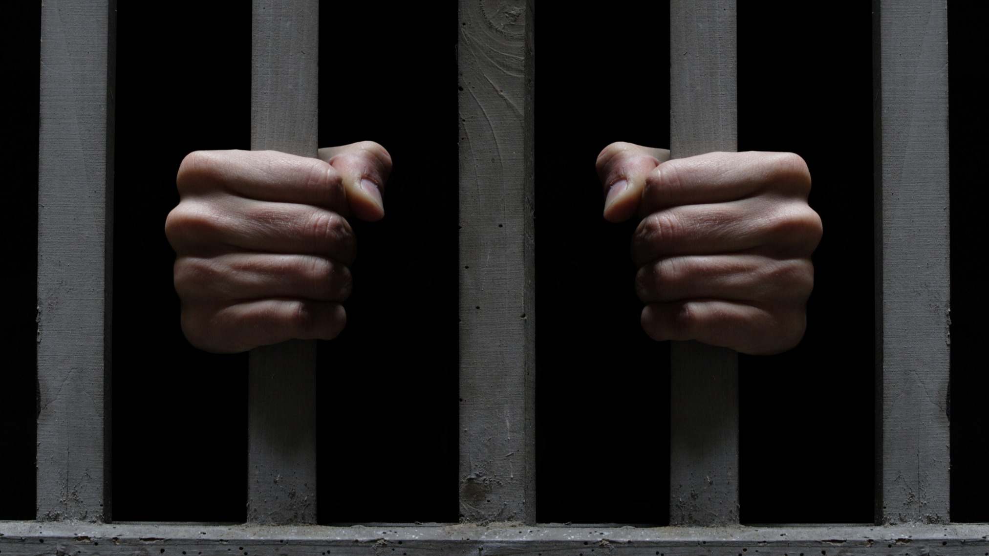 Manos de un preso entre rejas de una cárcel
