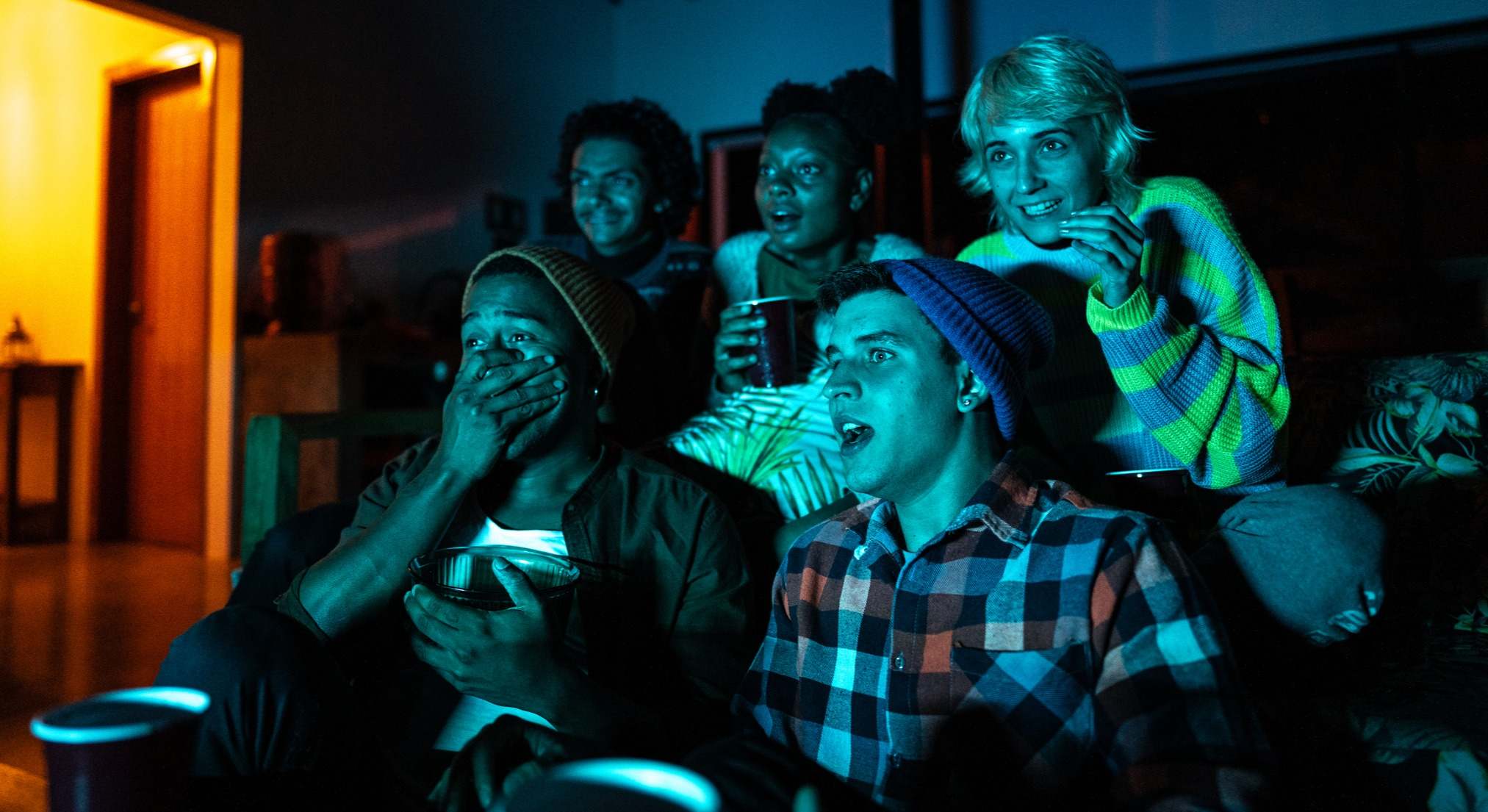 Personas viendo la televisión con la luz apagada