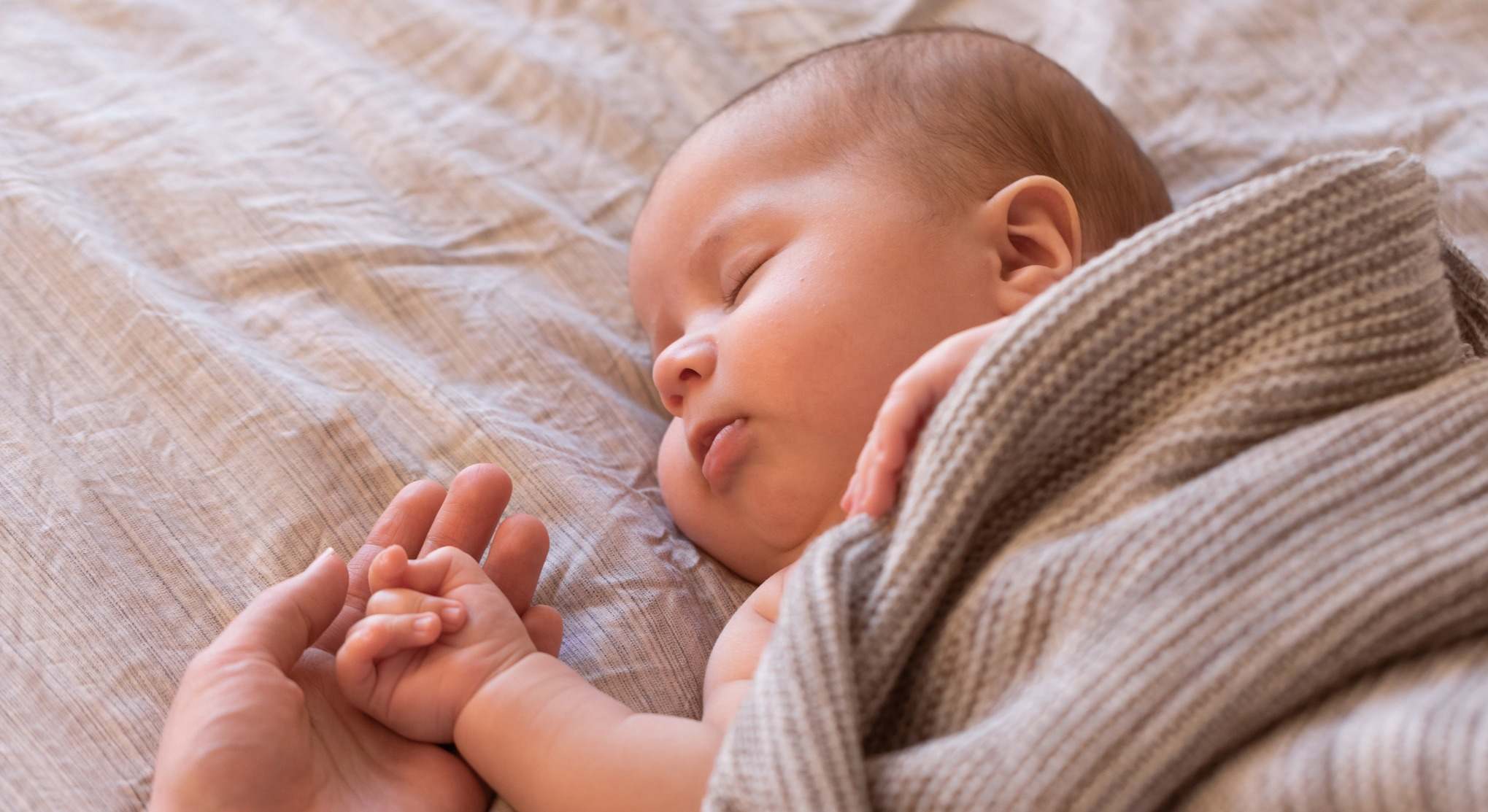 Bebé dormido con la mano de su madre