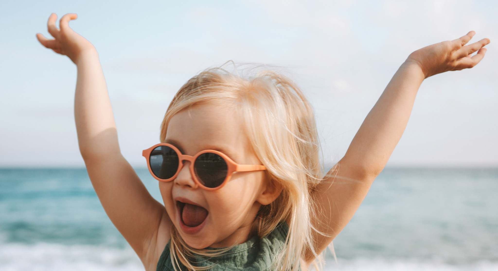 Niña con los brazos subidos en la playa