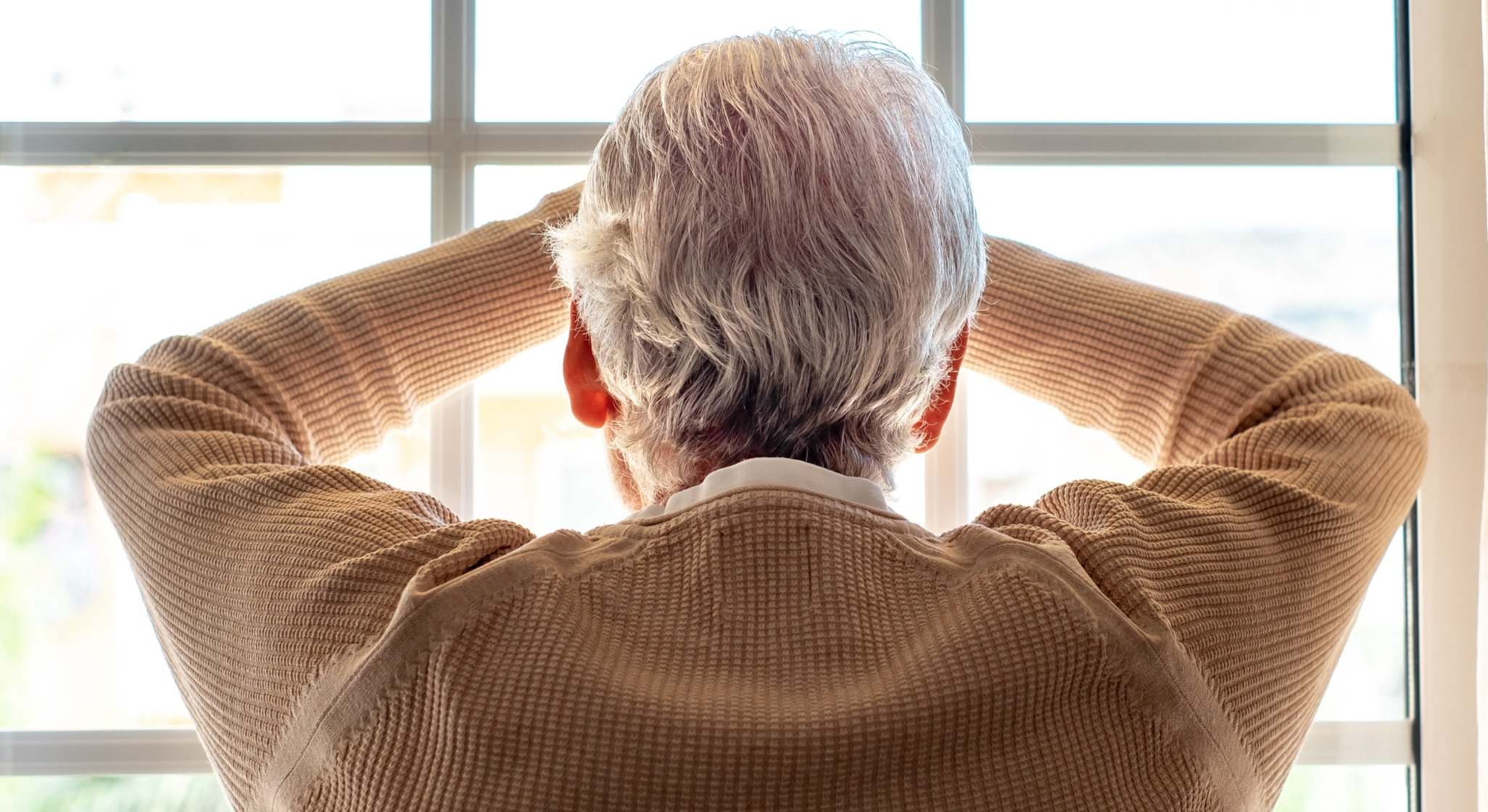 Hombre mayor apoyado en la ventana