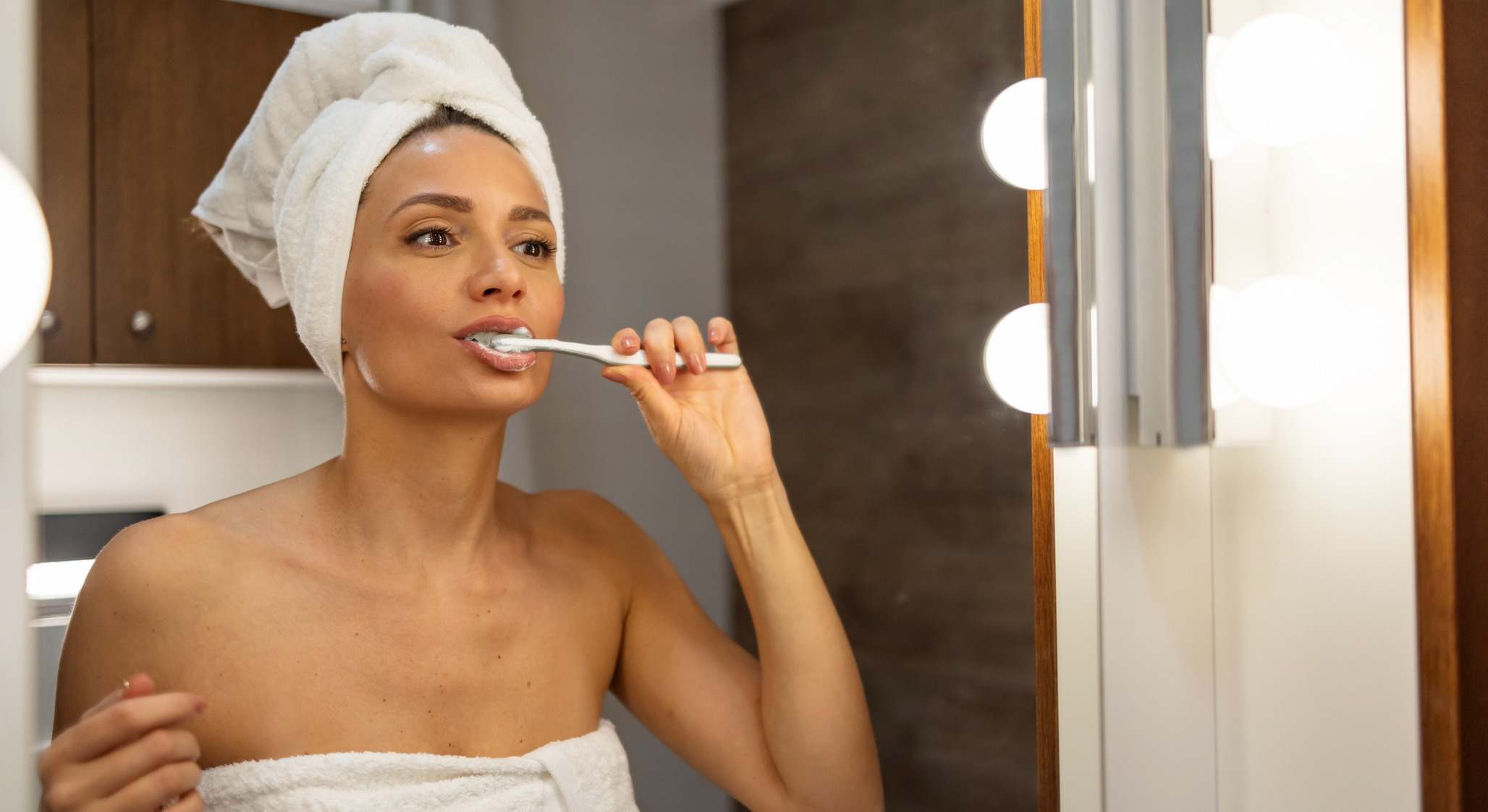Mujer en toalla cepillándose los dientes