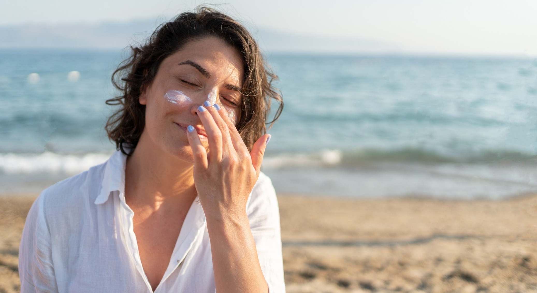 Mujer aplicándose crema solar en la cara