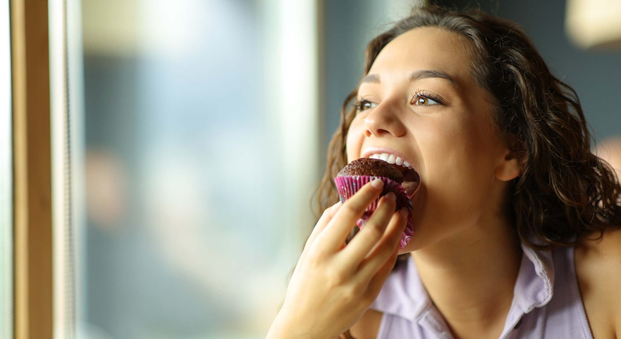 Mujer mordiendo una magdalena de chocolate