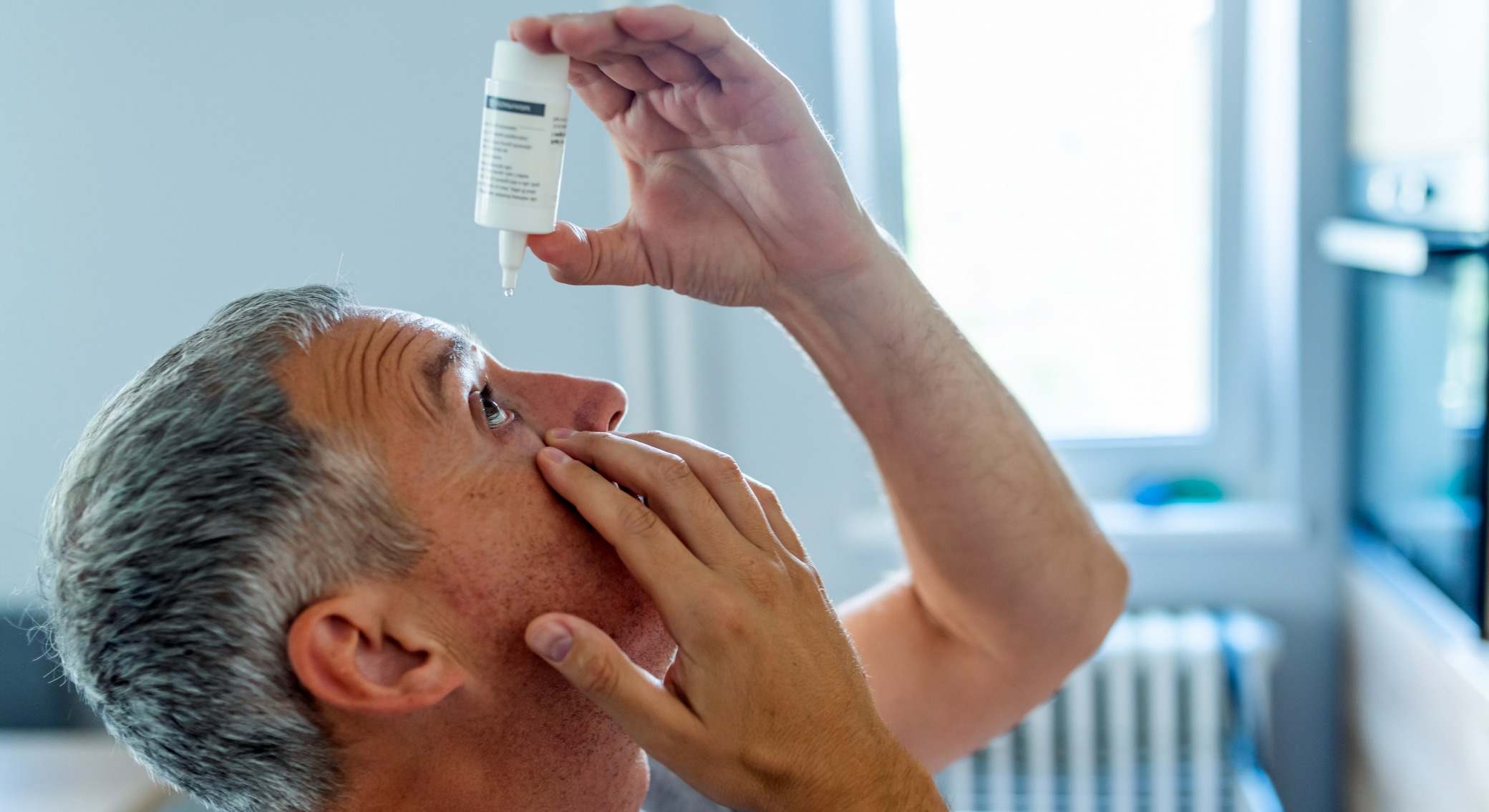 Hombre echándose colirio en los ojos