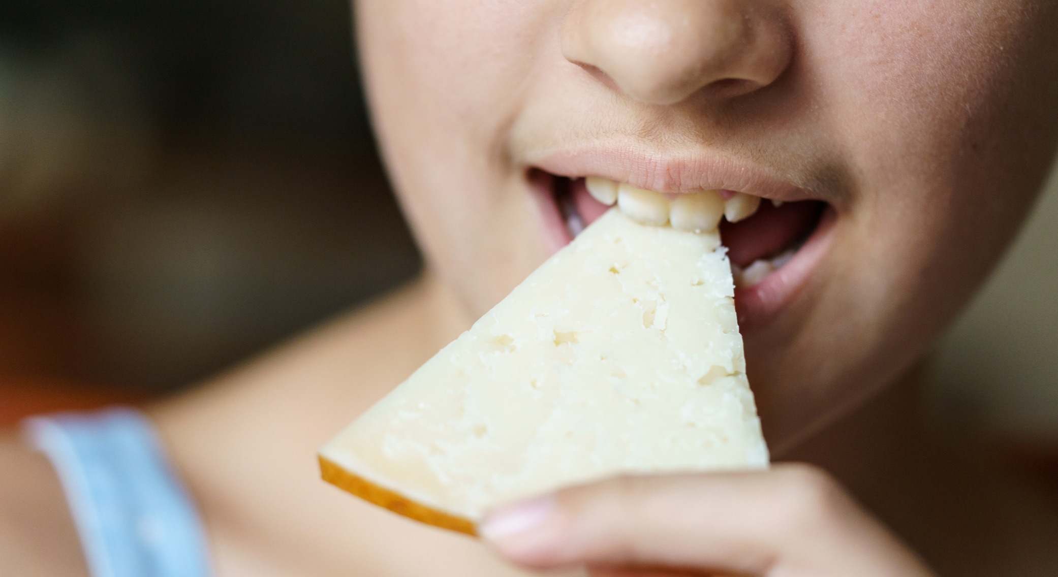 Una chica comiendo un trozo de queso