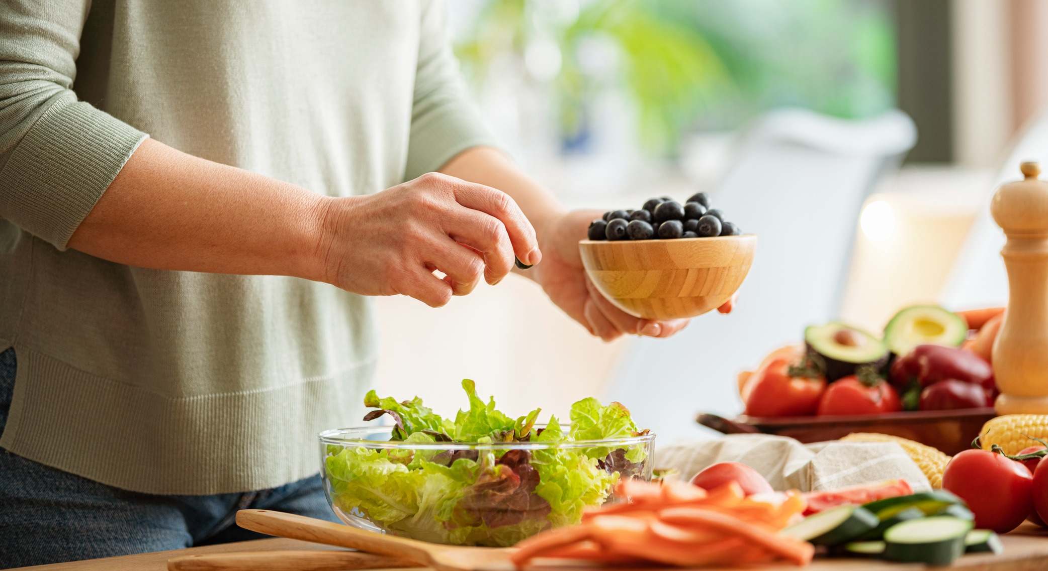 Mano añadiendo frutas a una ensalada