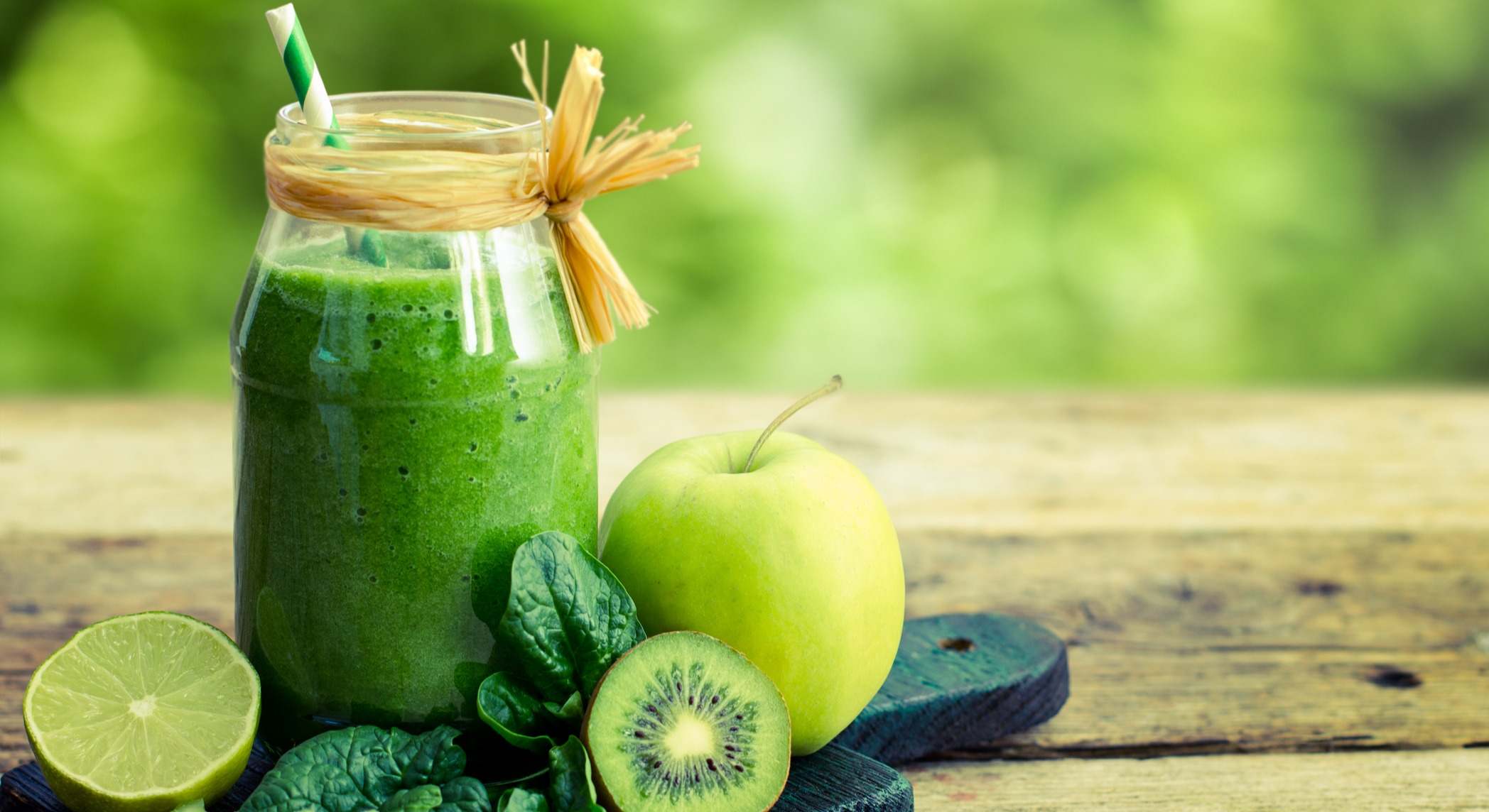 Batido verde dentro de un frasco sobre una mesa de madera
