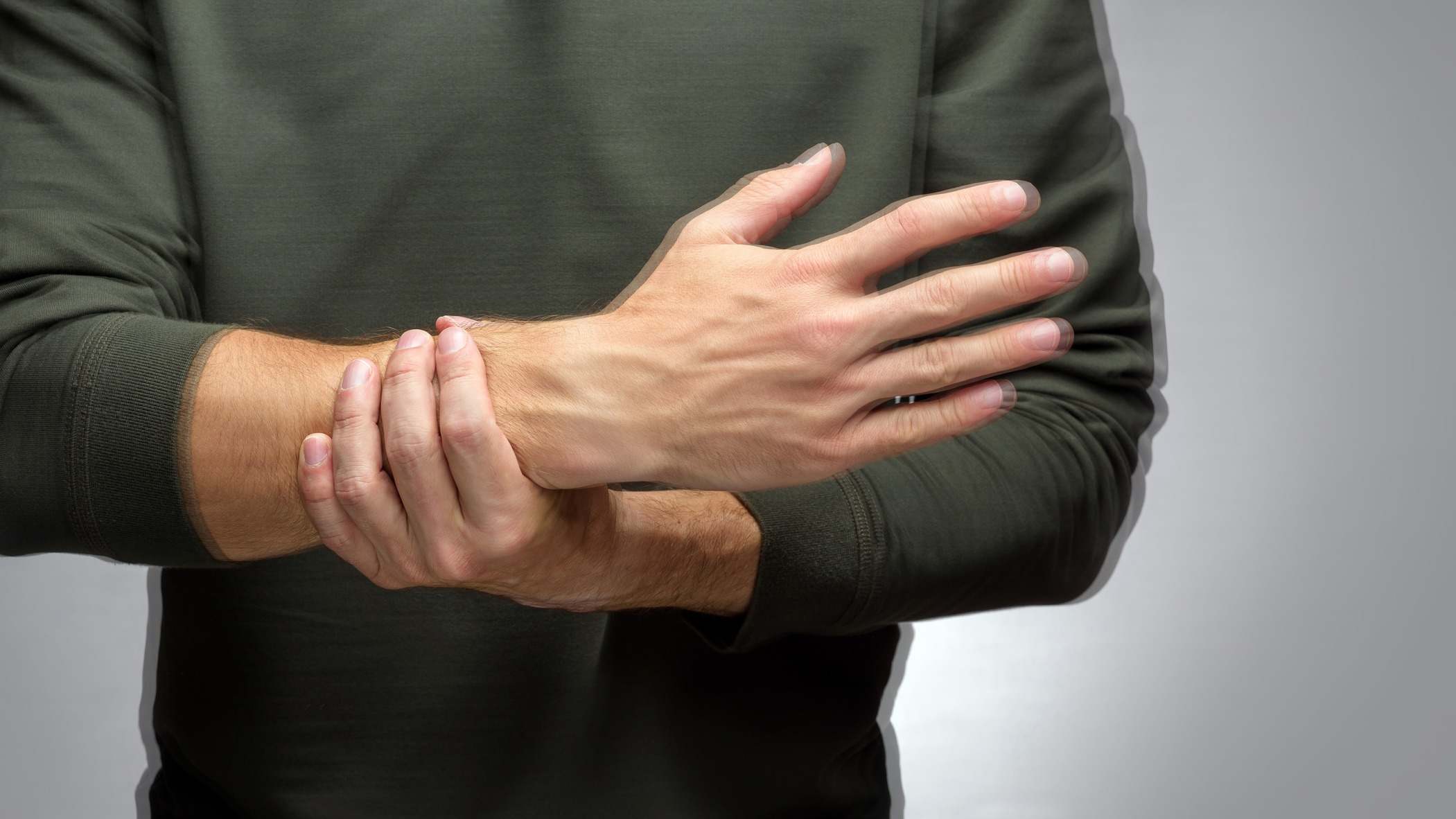 Un hombre con un temblor trata de evitar que su mano tiemble