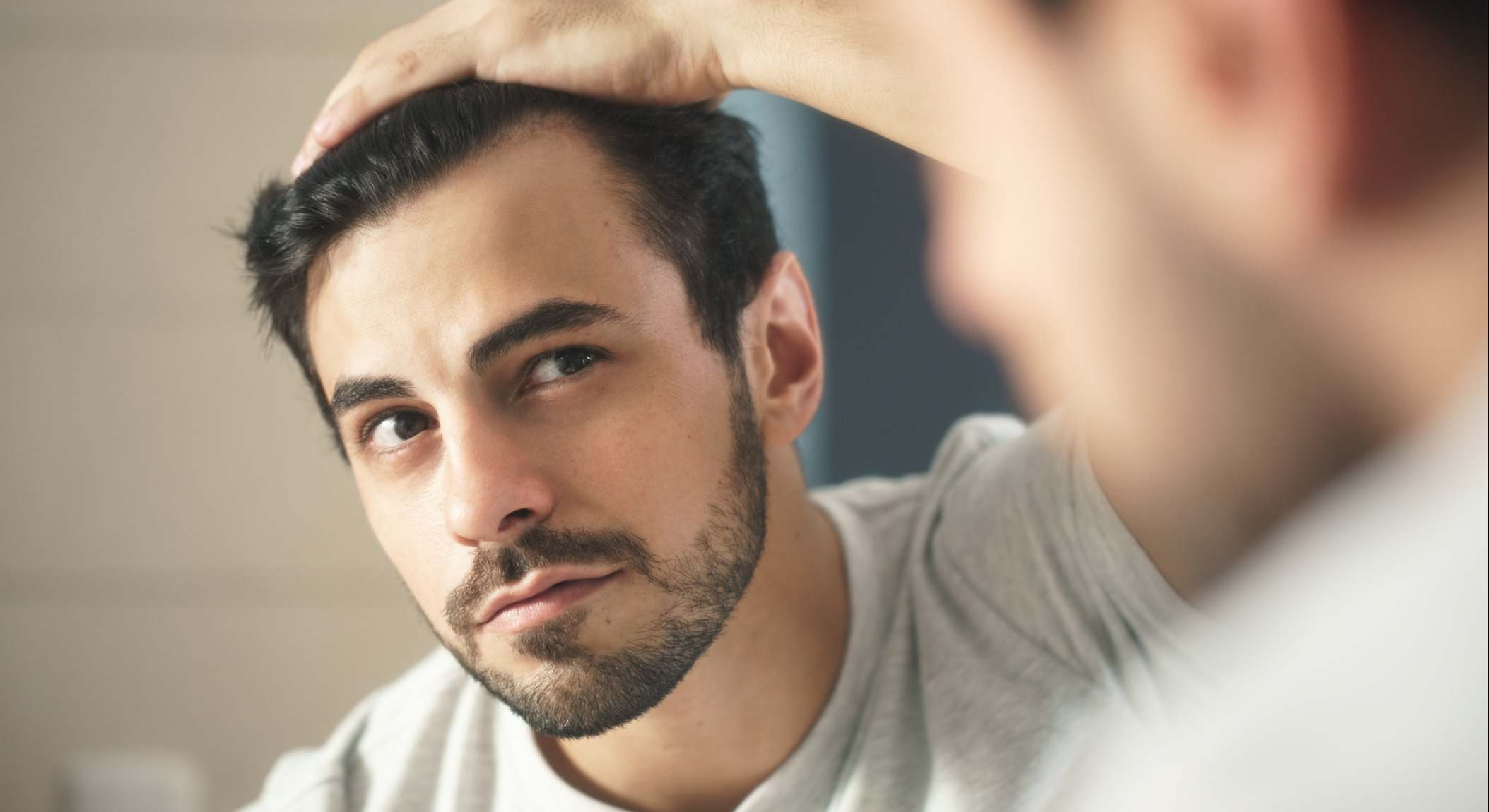 Hombre mirándose al espejo preocupado para la comprobación de pérdida de cabello