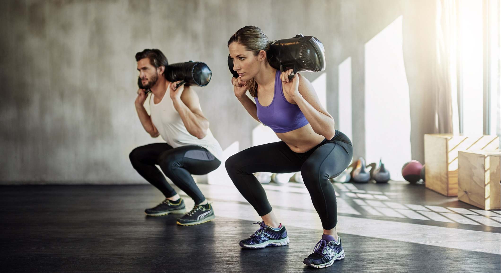 Mujer y hombre entrenando los glúteos en un gimnasio