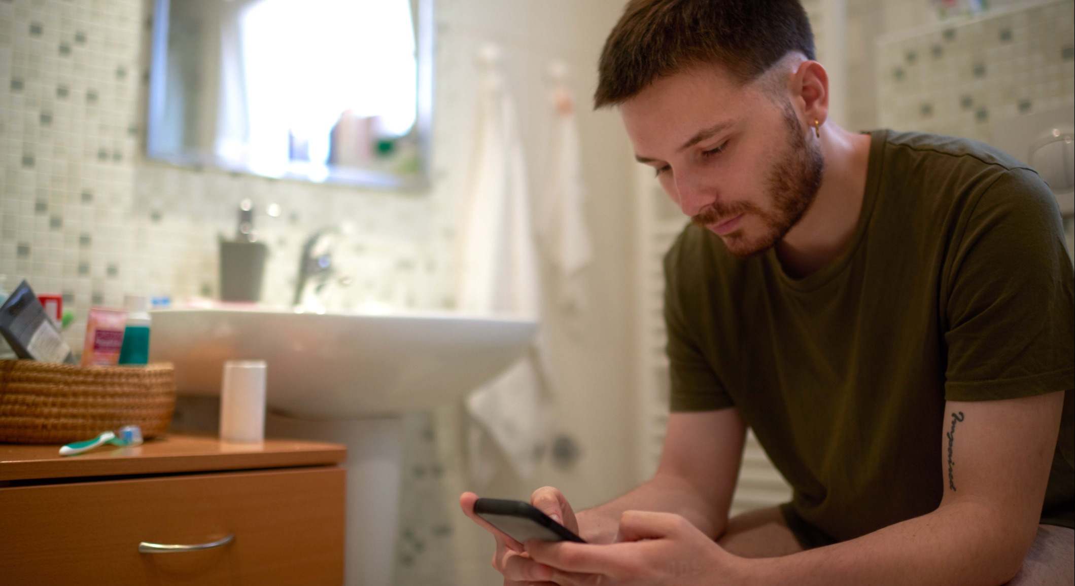 Hombre en el baño usando el móvil