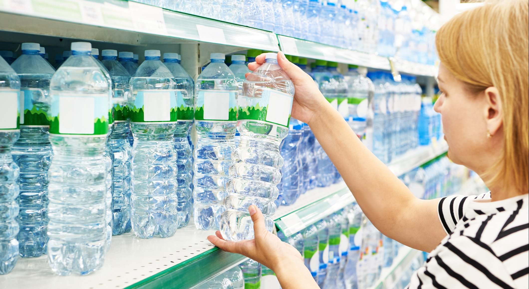 Mujer eligiendo botellas de agua en un supermercado