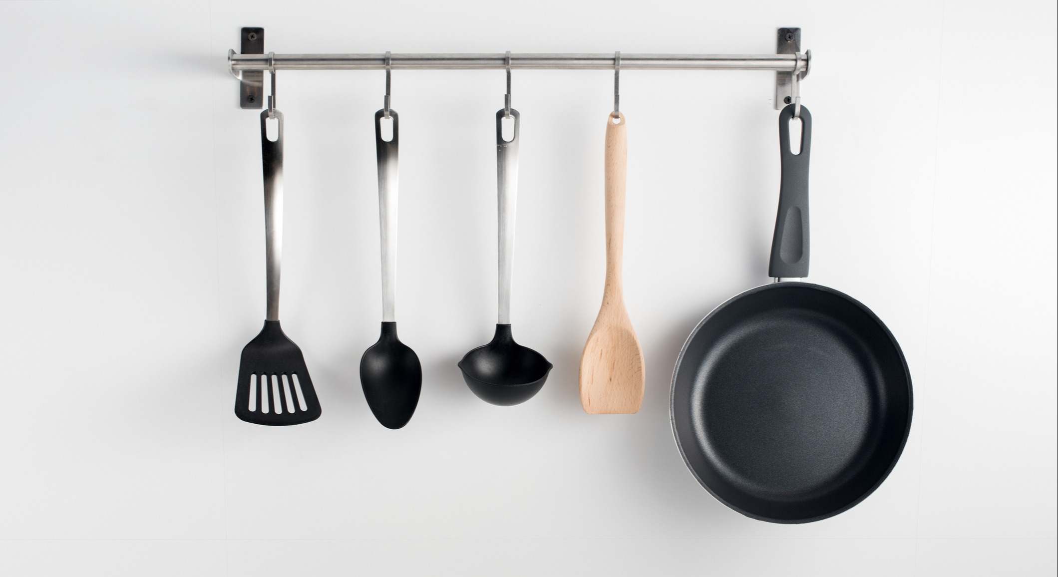 Utensilios de cocina colgados en una barra en la pared
