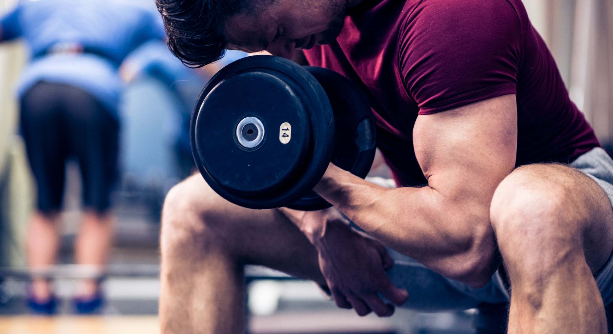 Hombre realizando ejercicios de brazos con pesas en un gimnasio