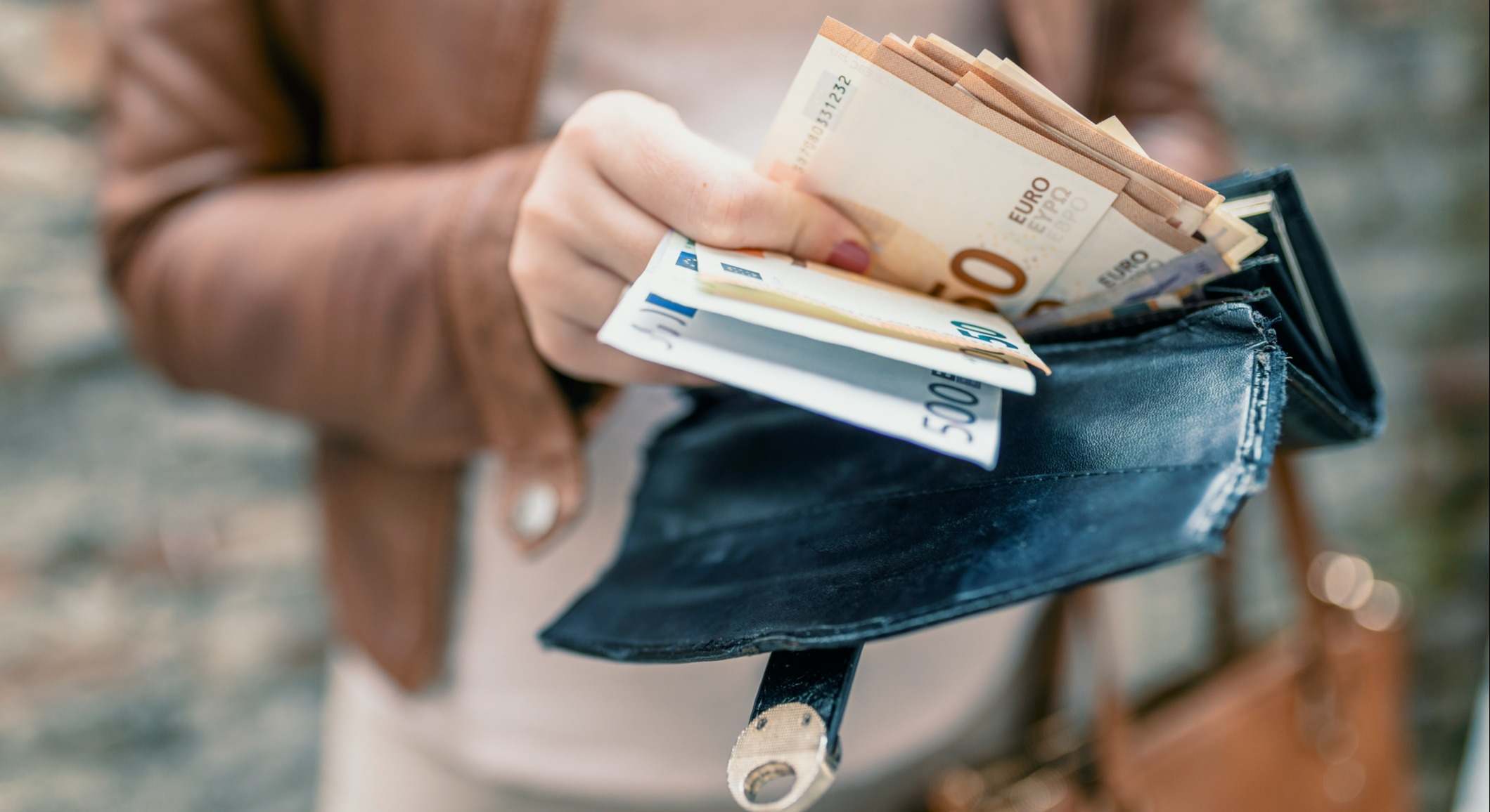 Una mujer sujetando un monedero con billetes de euro. Foto: iStock