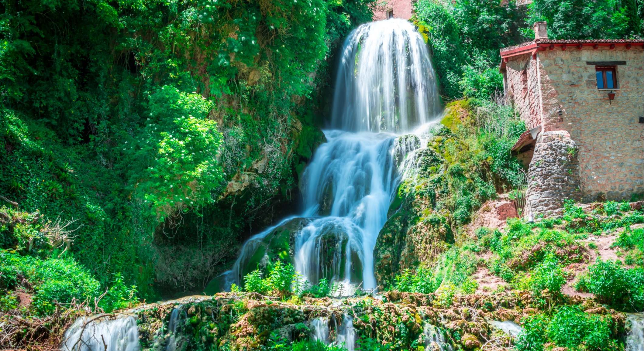 Cascada de Orbaneja del Castillo que divide la villa en dos y está rodeado de vegetación
