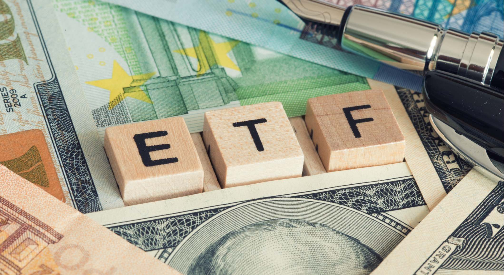 Imagen de fichas con las siglas ETF encima de billetes