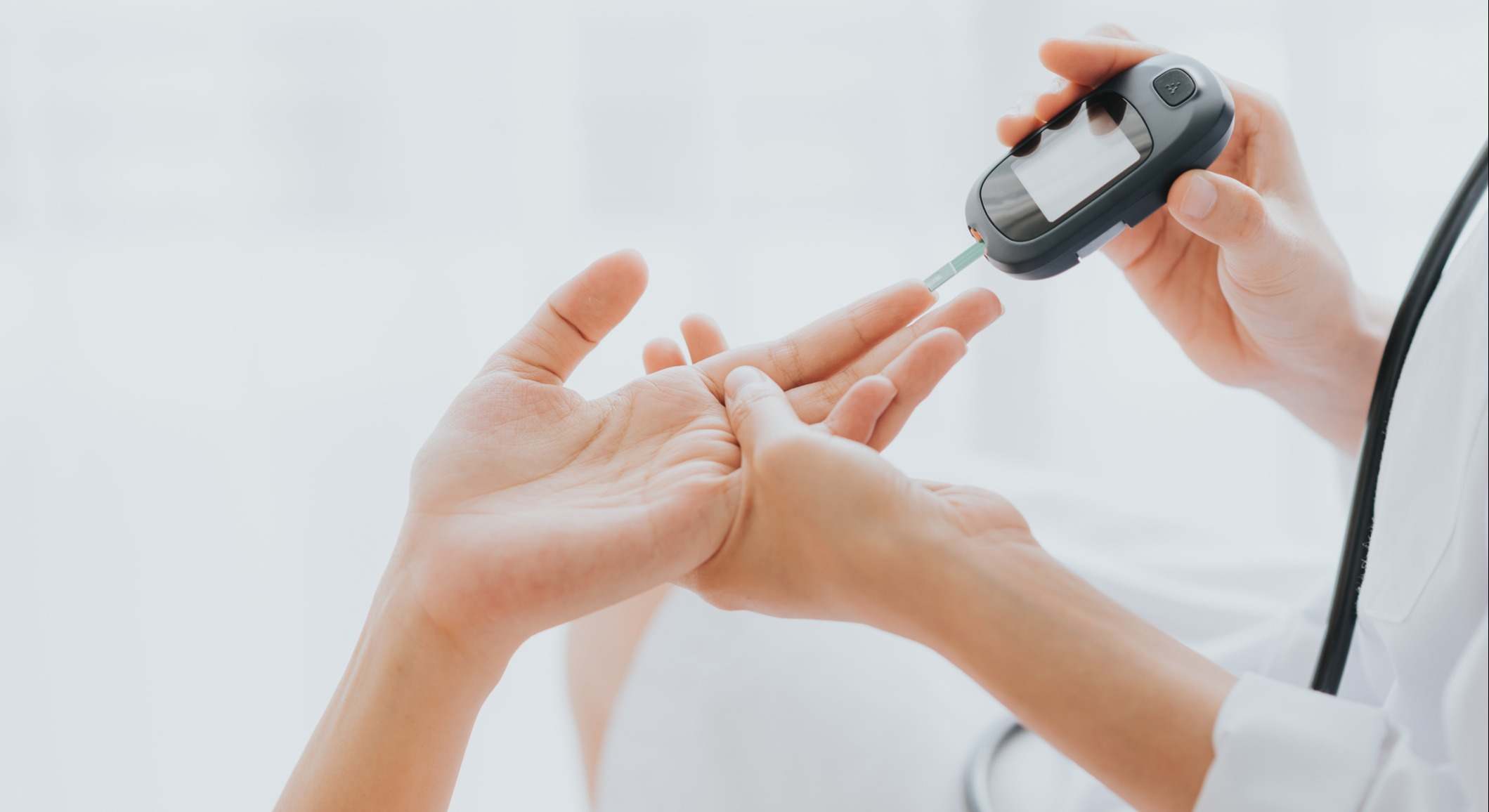 Médico utiliza glucómetro con la mano del paciente