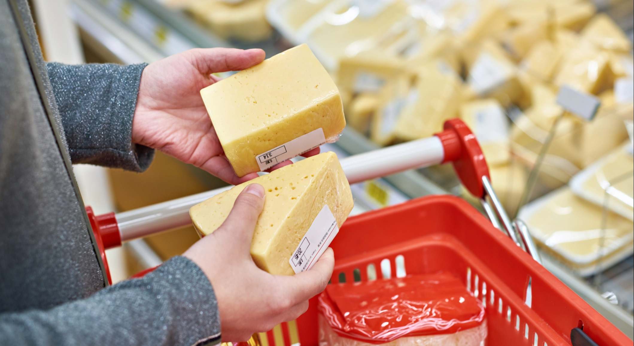 Persona en un supermercado con un queso en cada mano