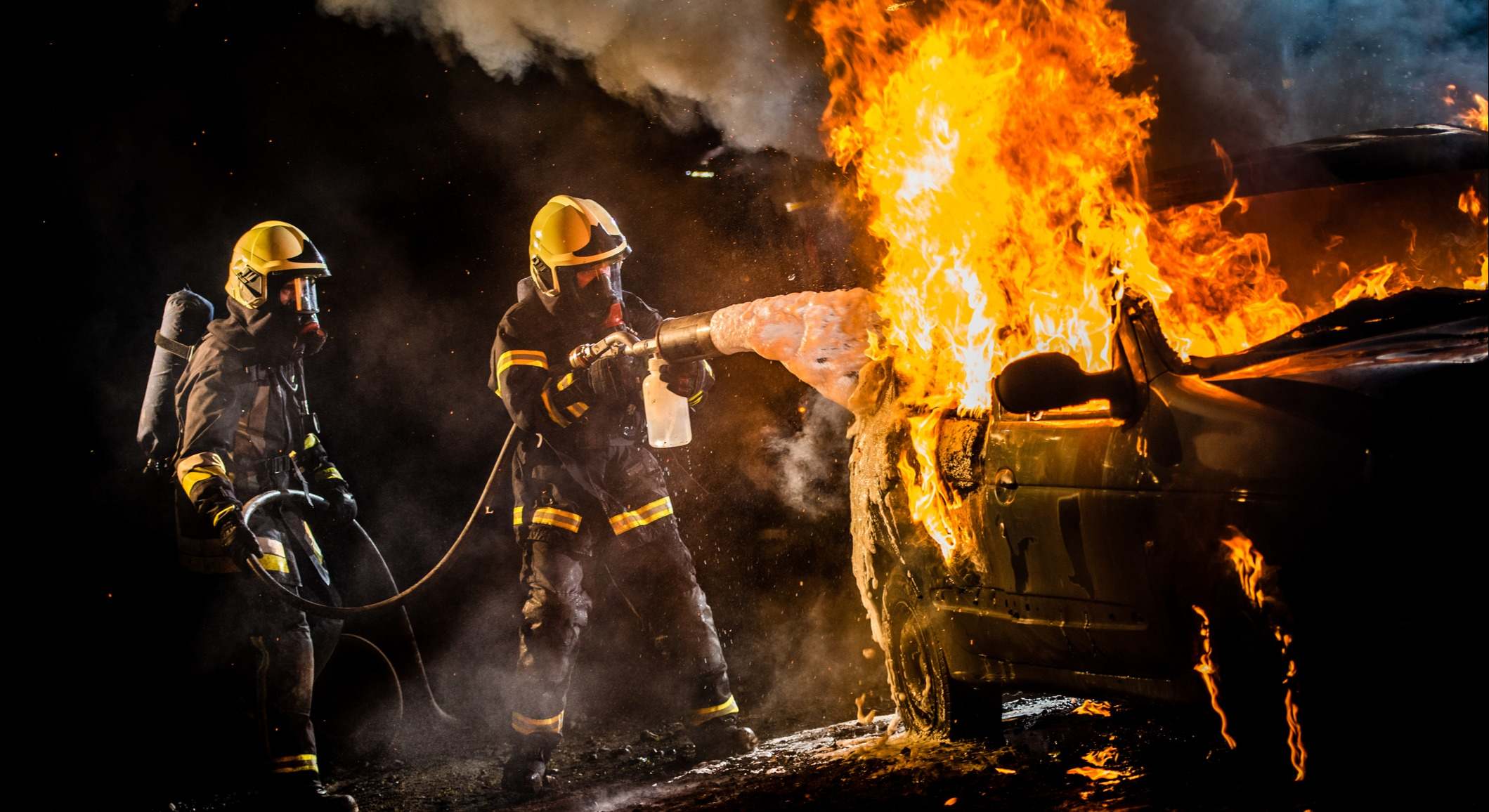 Bomberos apagando el fuego de un coche ardiendo