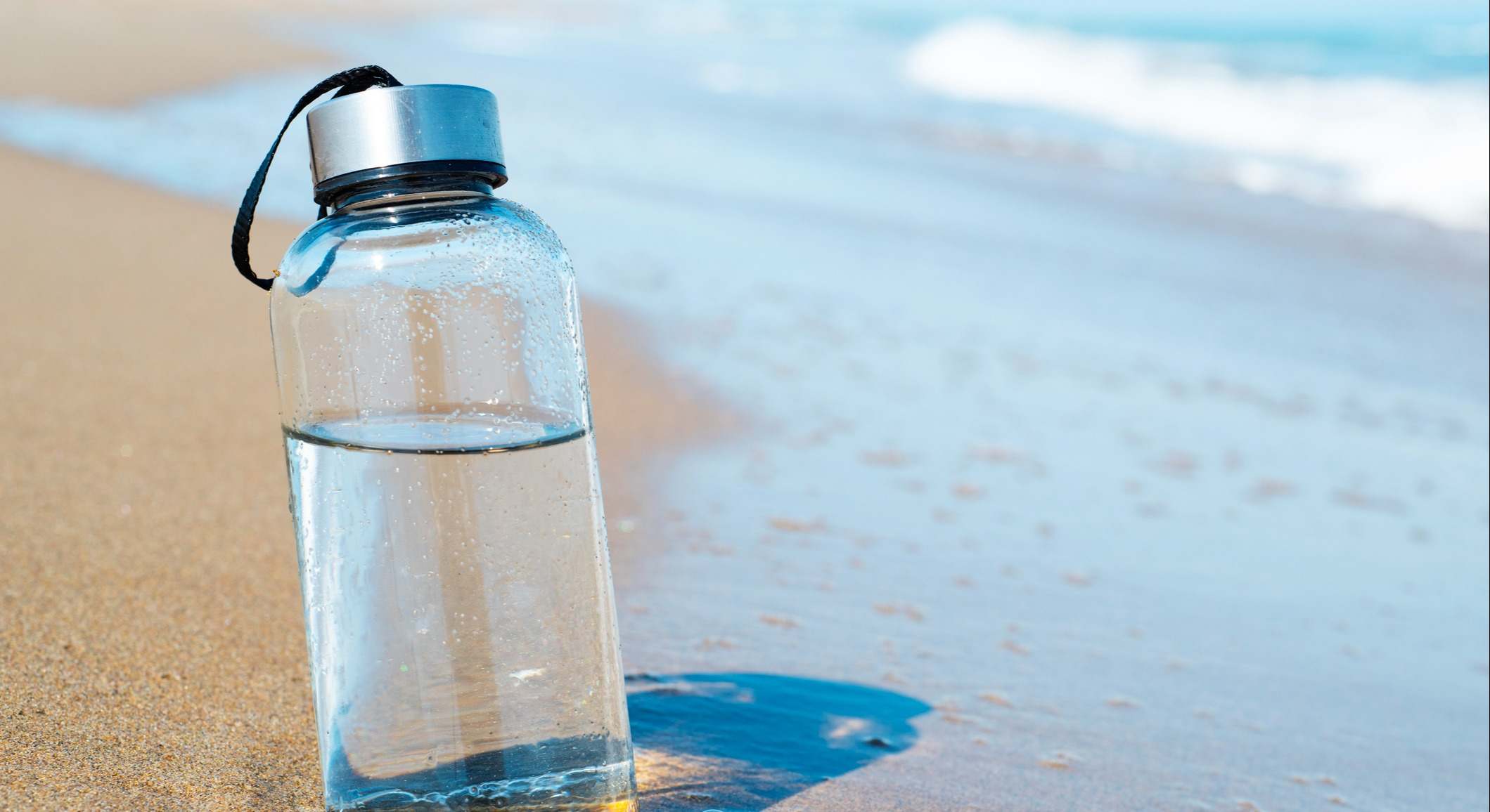 Botella de agua reutilizable en la playa