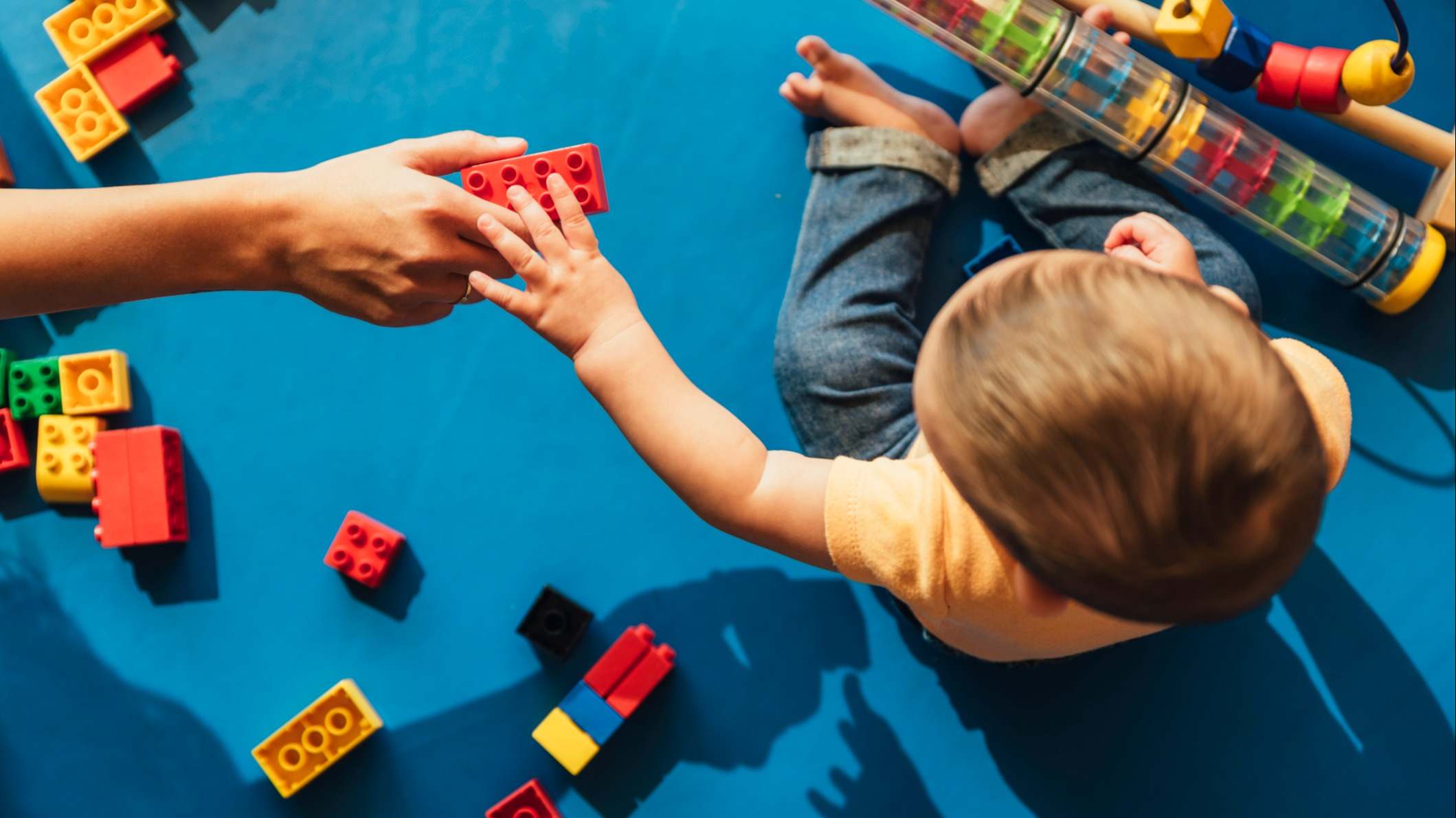 Niño jugando con piezas en el suelo.