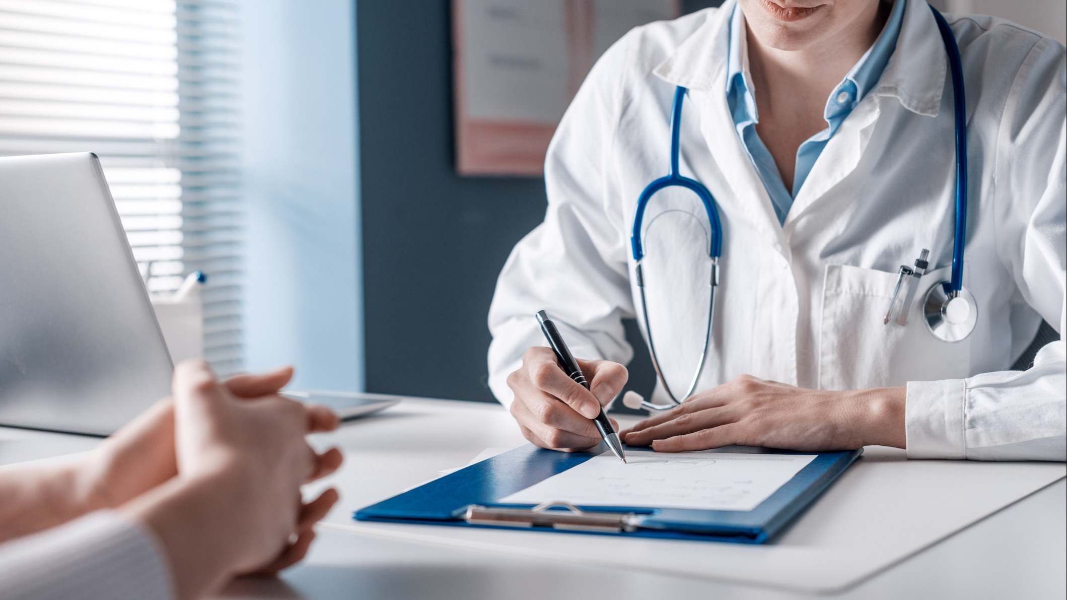 Médico que escribe una receta médica en su consulta