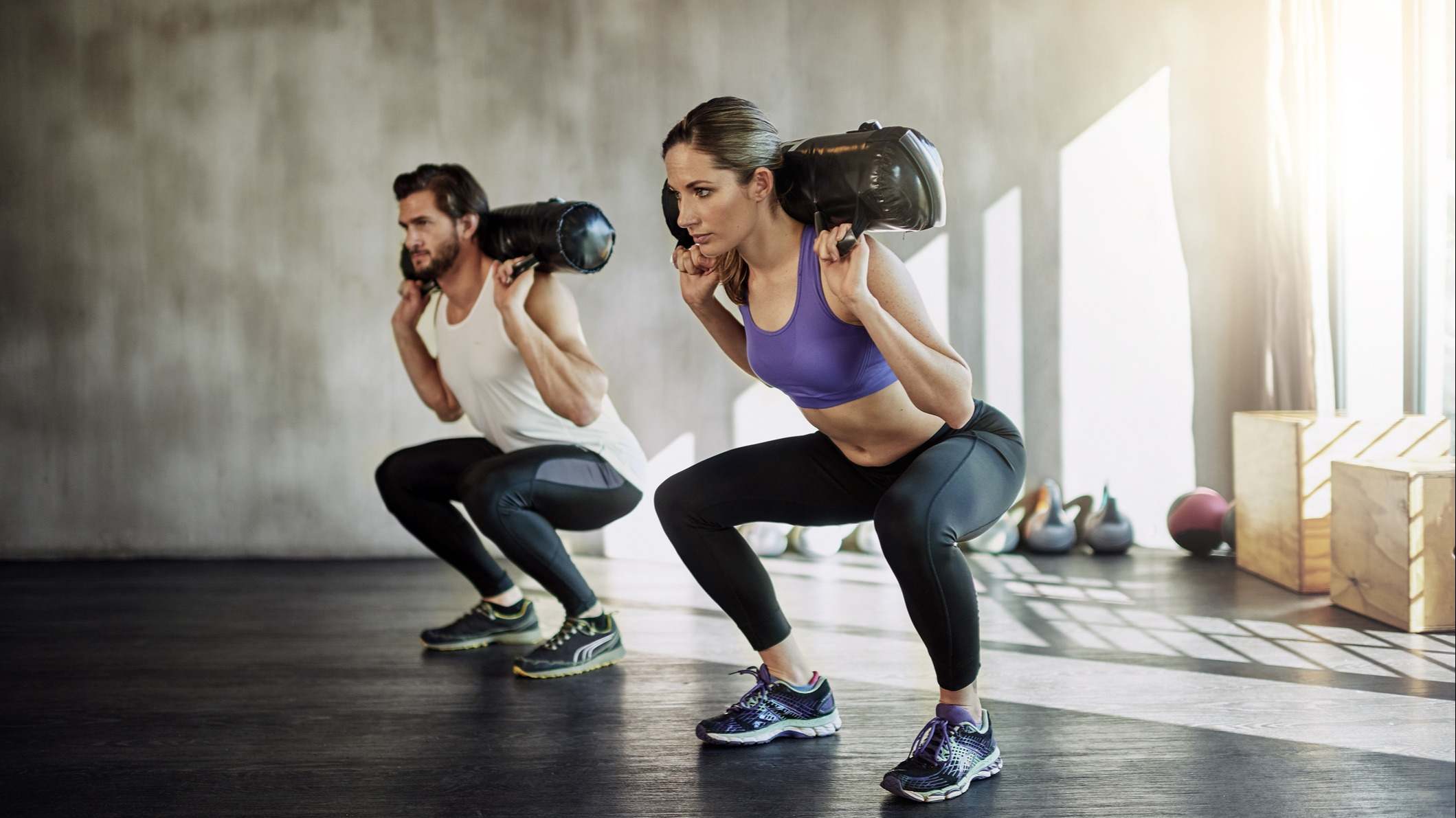 Hombre y mujer haciendo sentadillas con peso