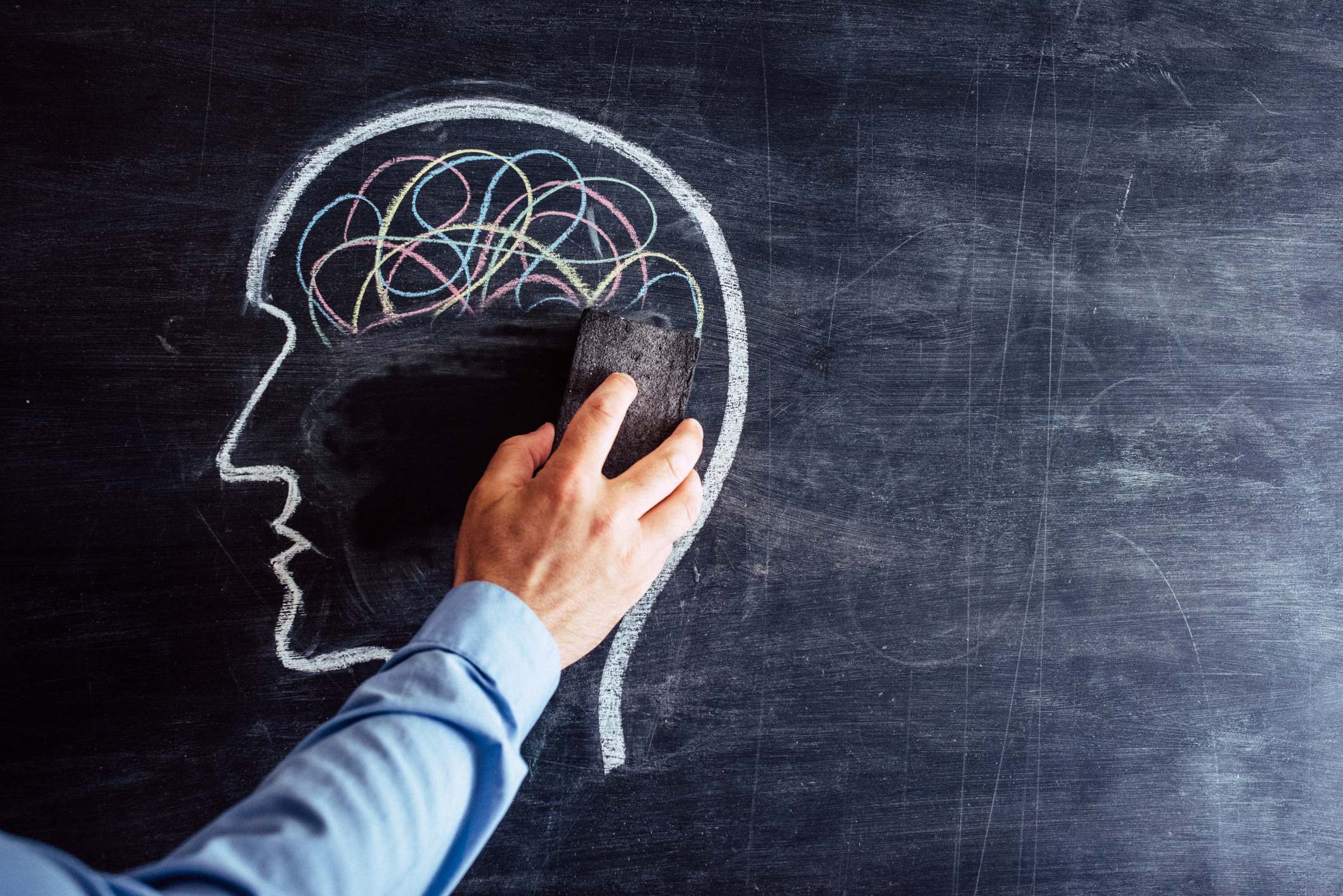 Un hombre borra de una pizarra un cerebro dibujado