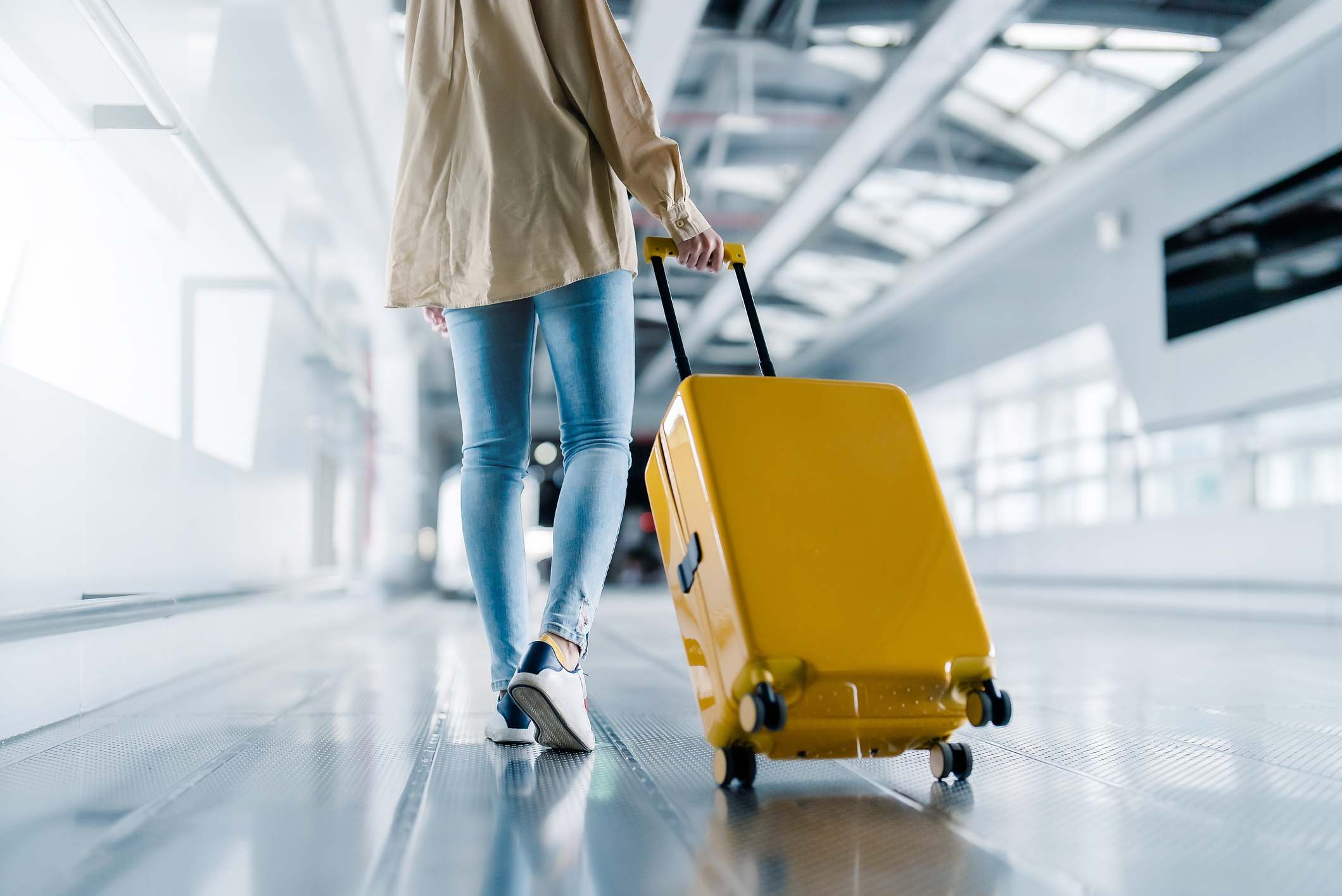 Terminal del aeropuerto internacional. Hermosa mujer asiática con equipaje y caminando en el aeropuerto