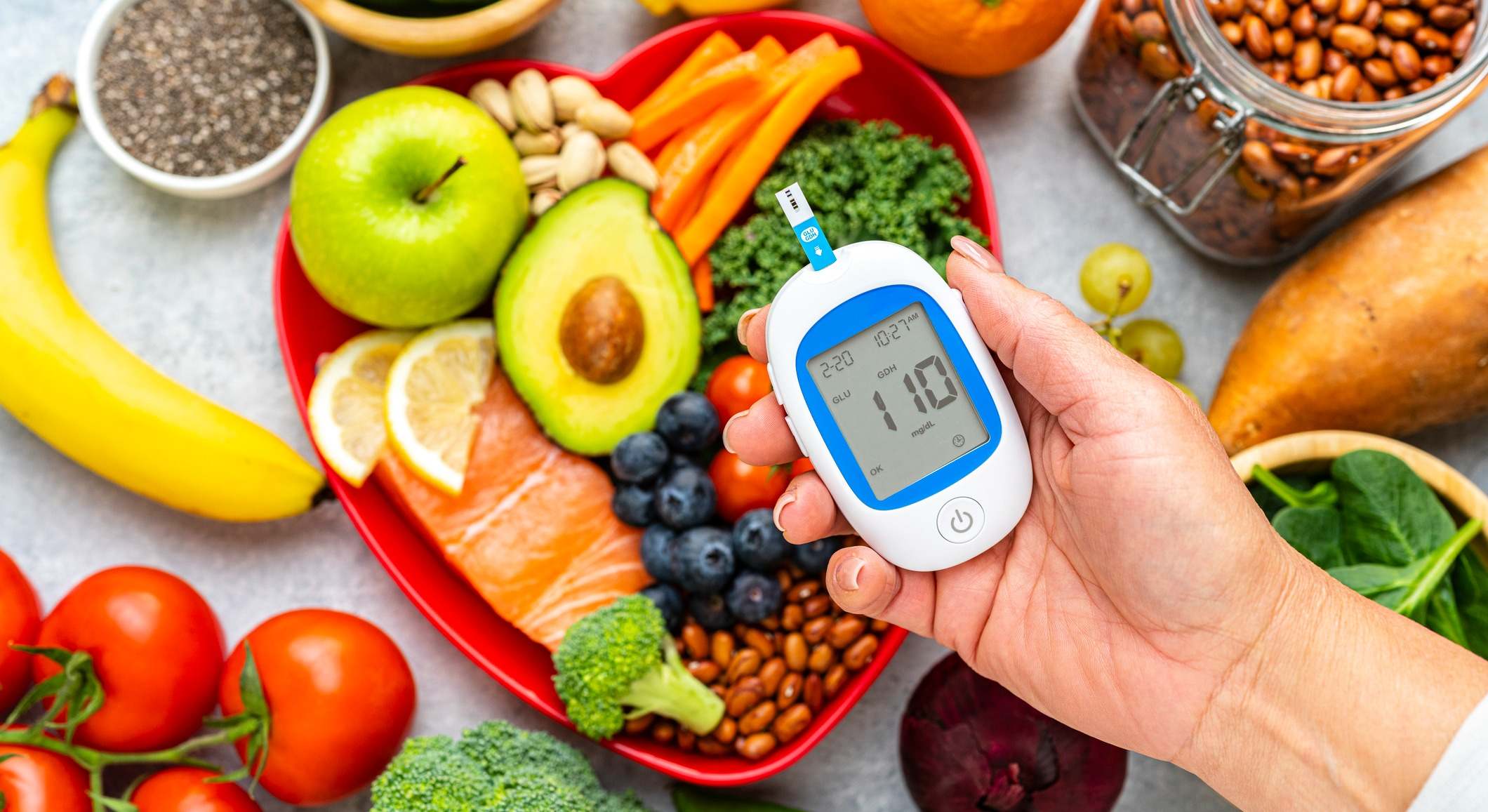 Mano sosteniendo el glucómetro en el fondo de la comida saludable