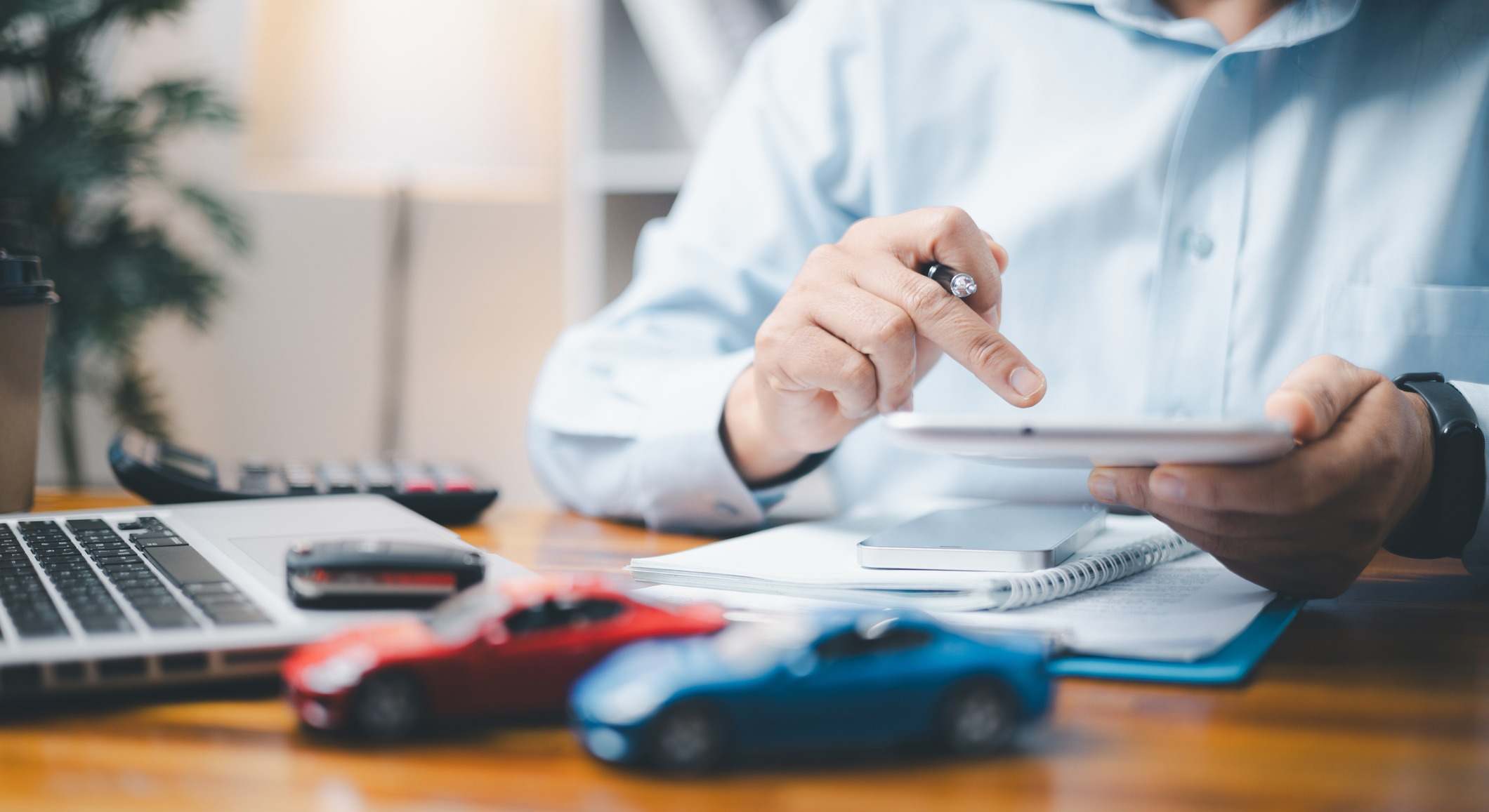 Coche de juguete frente a un hombre calculando el Impuesto de Matriculación