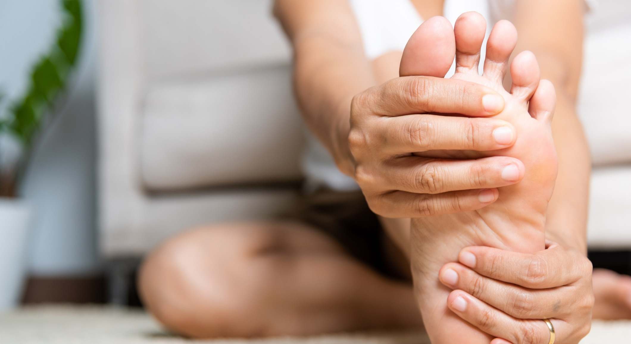 Mujer con dolor en el pie tocándose la planta del pie