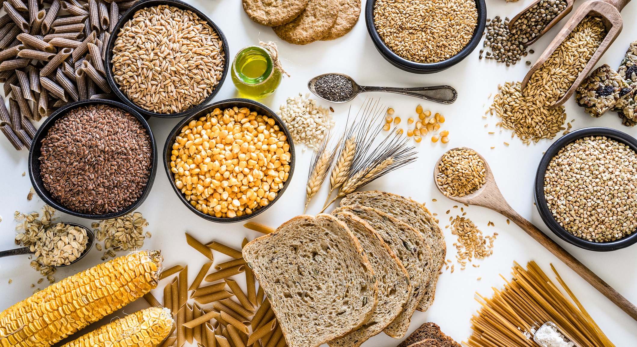 Grupo de alimentos integrales fotografiados desde arriba sobre fondo blanco