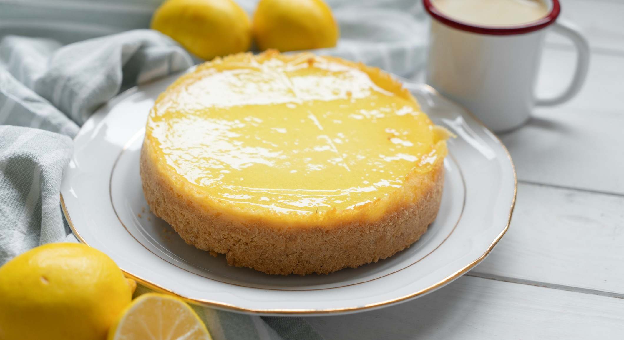 Pastel encima de una mesa con más limones y una taza de café