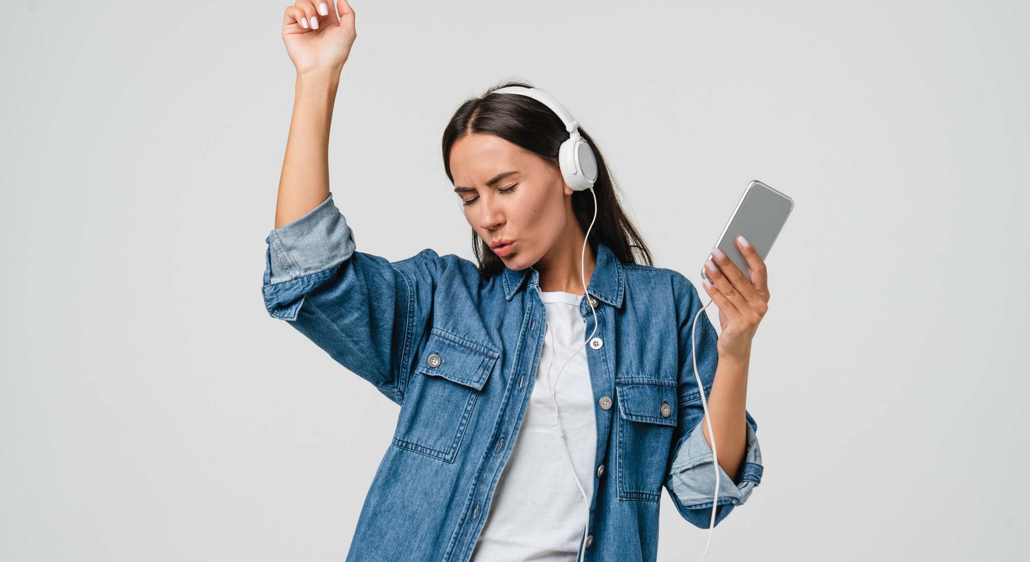 Mujer bailando mientras escucha música con unos auriculares conectados a su móvil