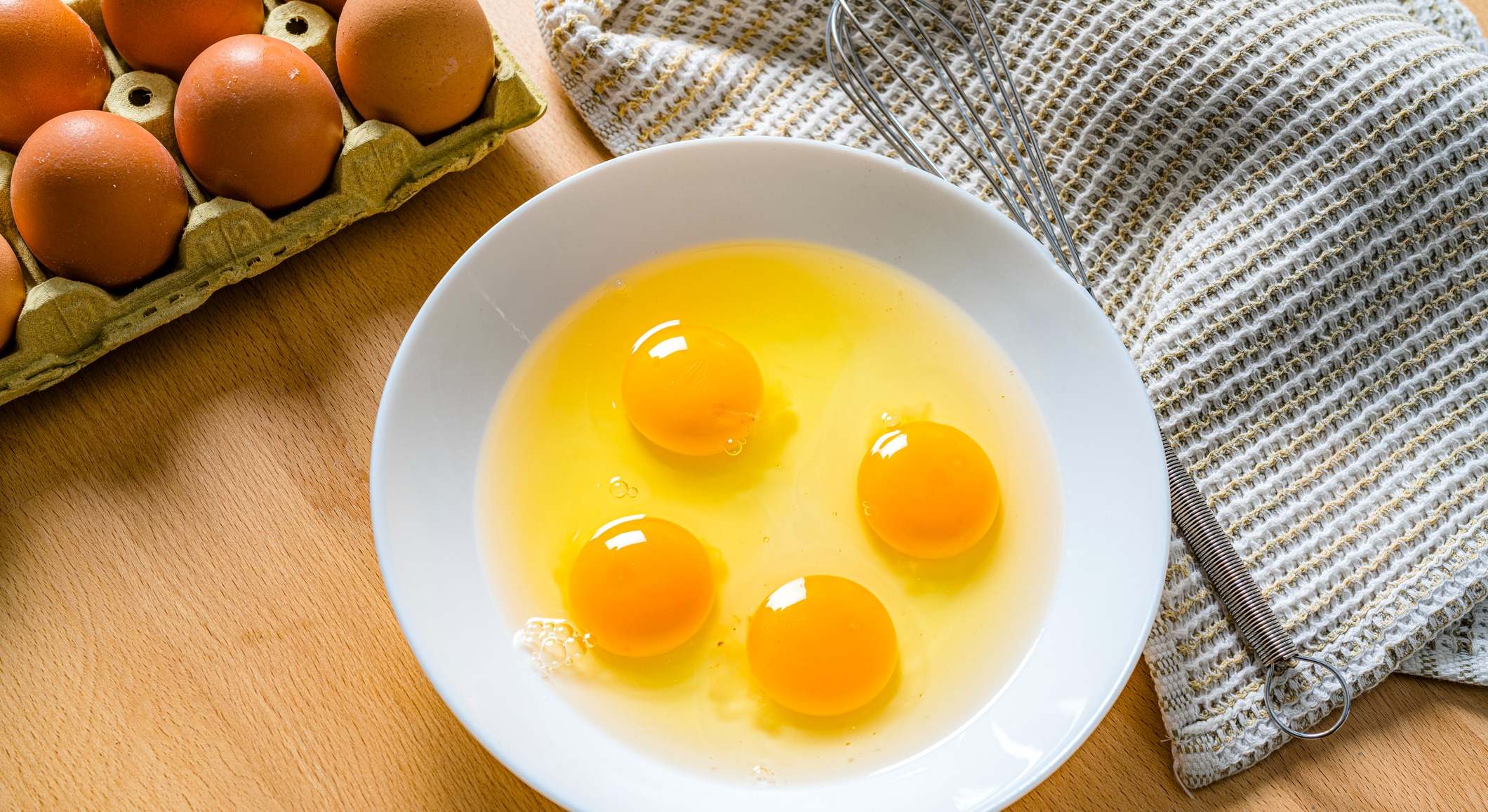 Cuatro huevos crudos en un bol blanco