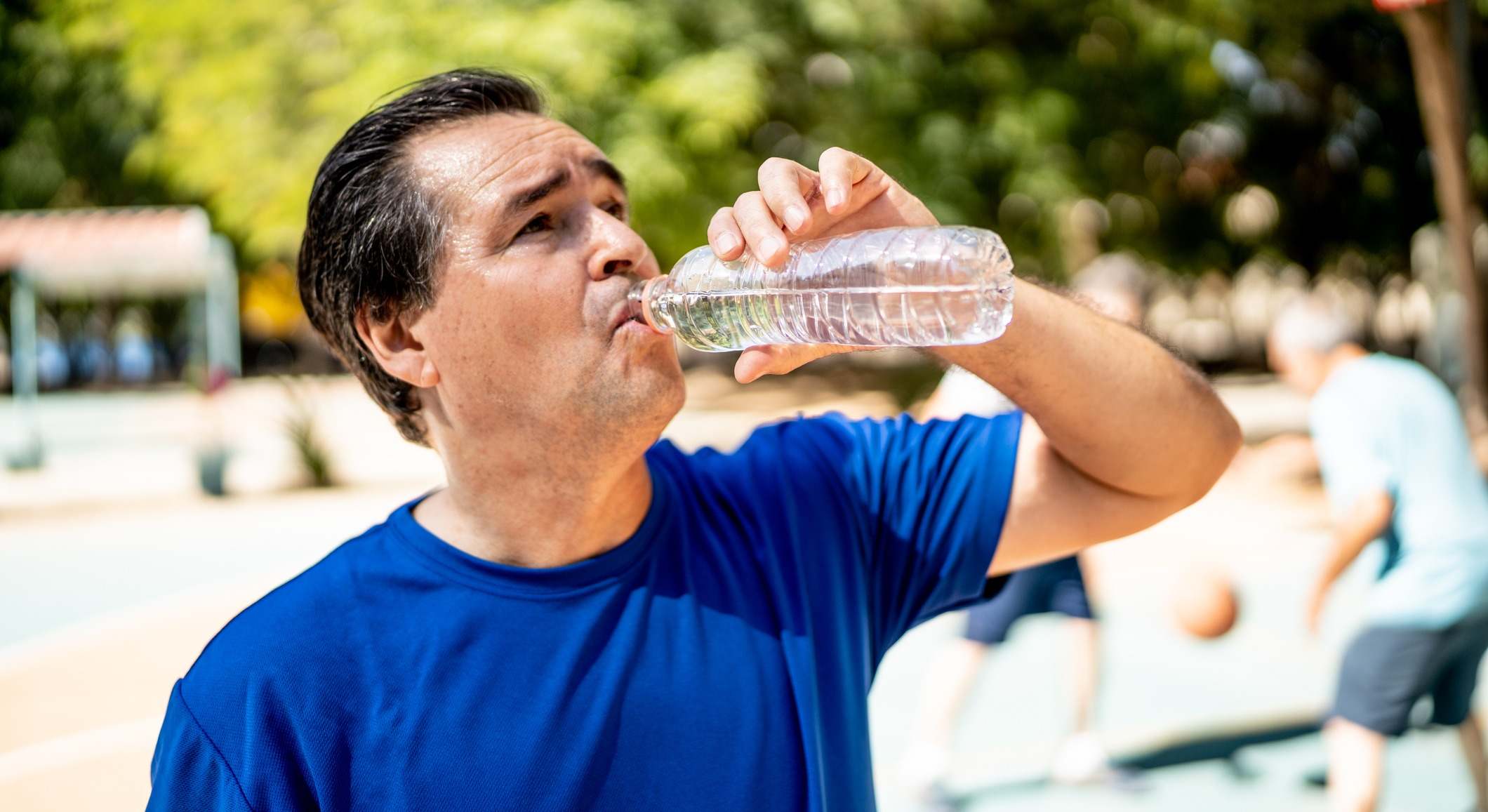 Hombre bebiendo agua de una botella de plástico