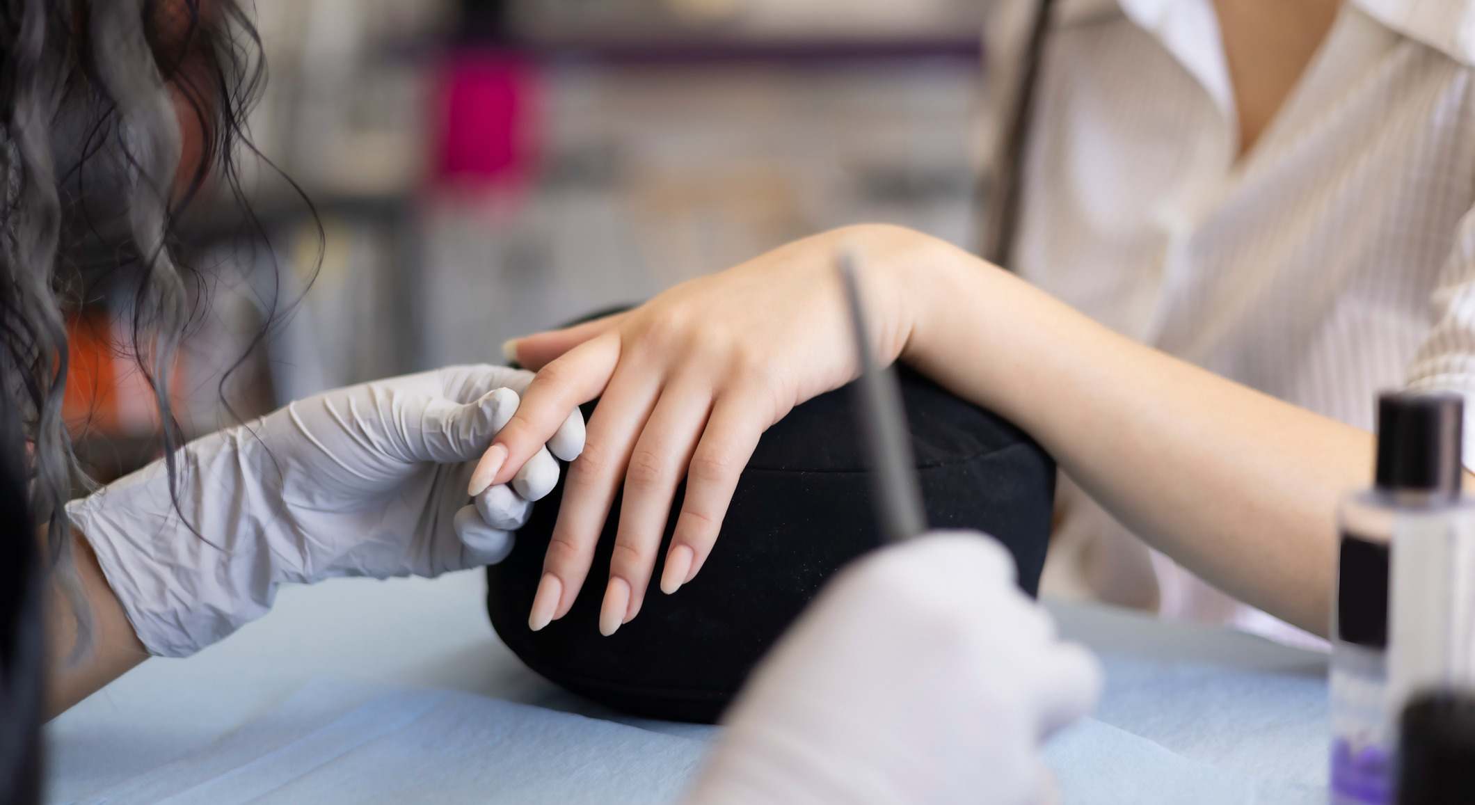 Manicurista aplicando acrílico en las uñas a una clienta