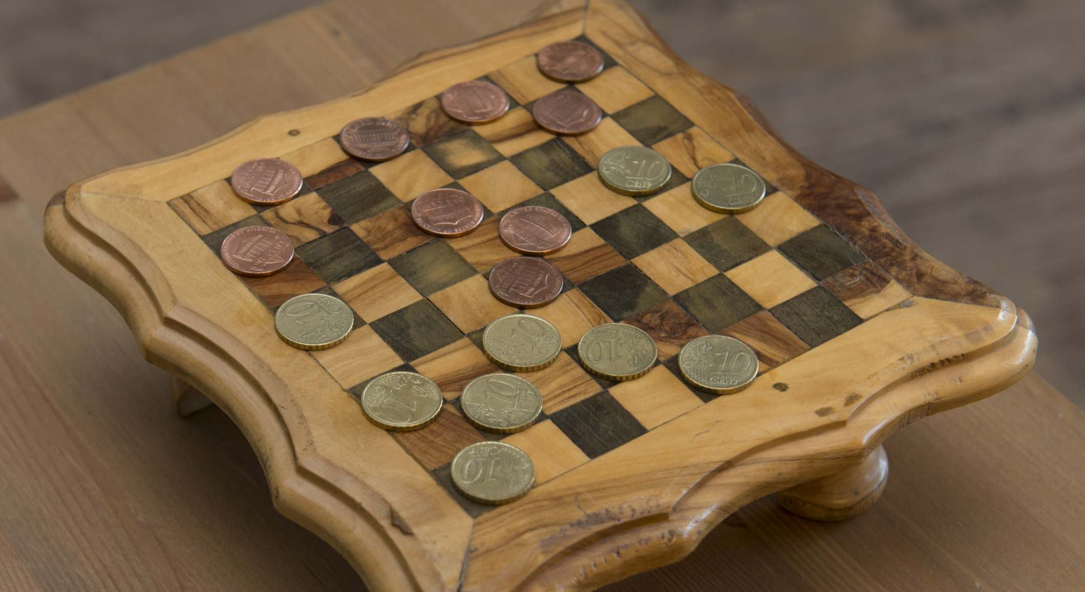 Un tablero de ajedrez en el que las fichas son monedas de céntimos de euro y de dólares