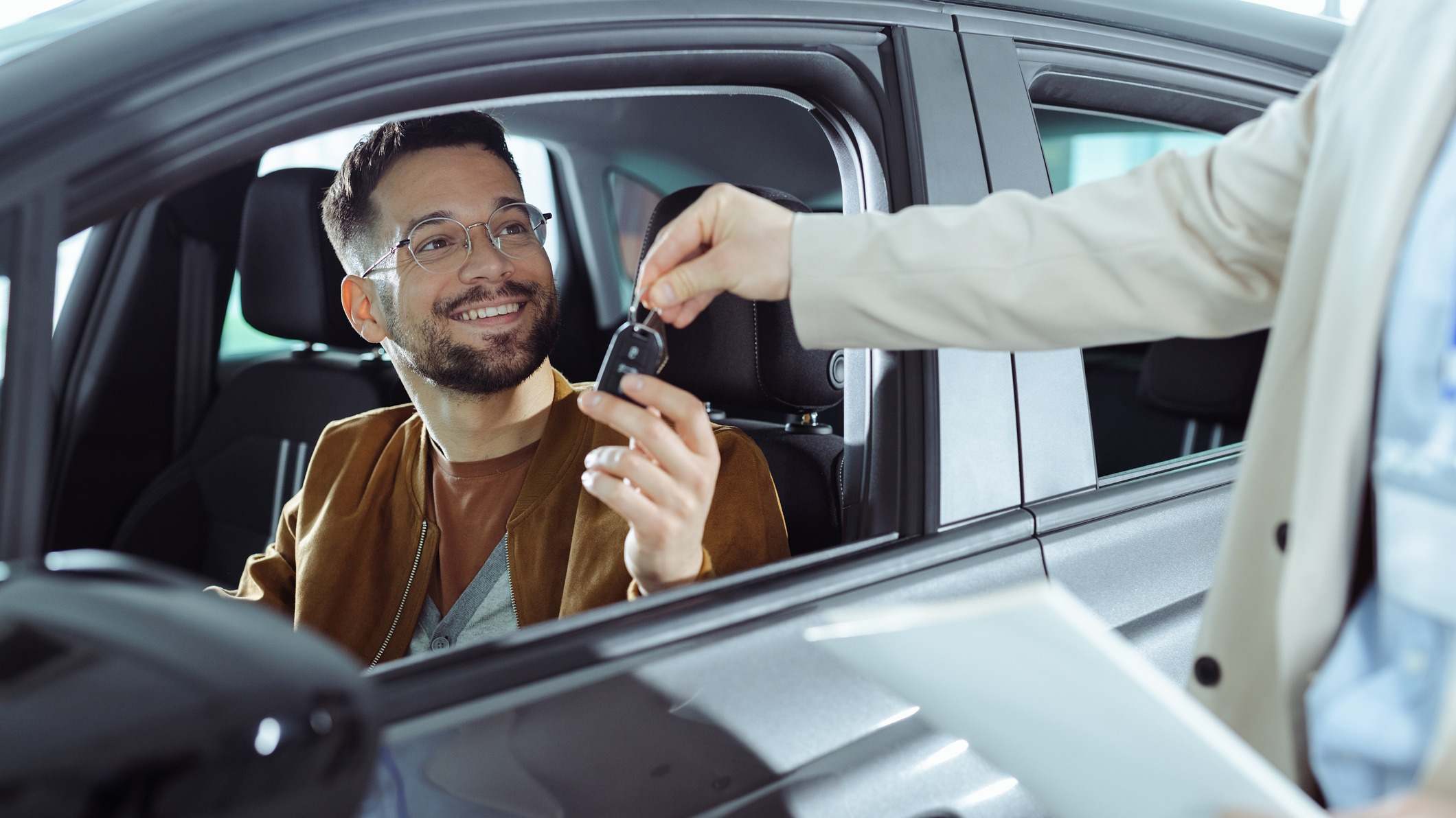 Un joven recibiendo las llaves de un coche después de comprarlo