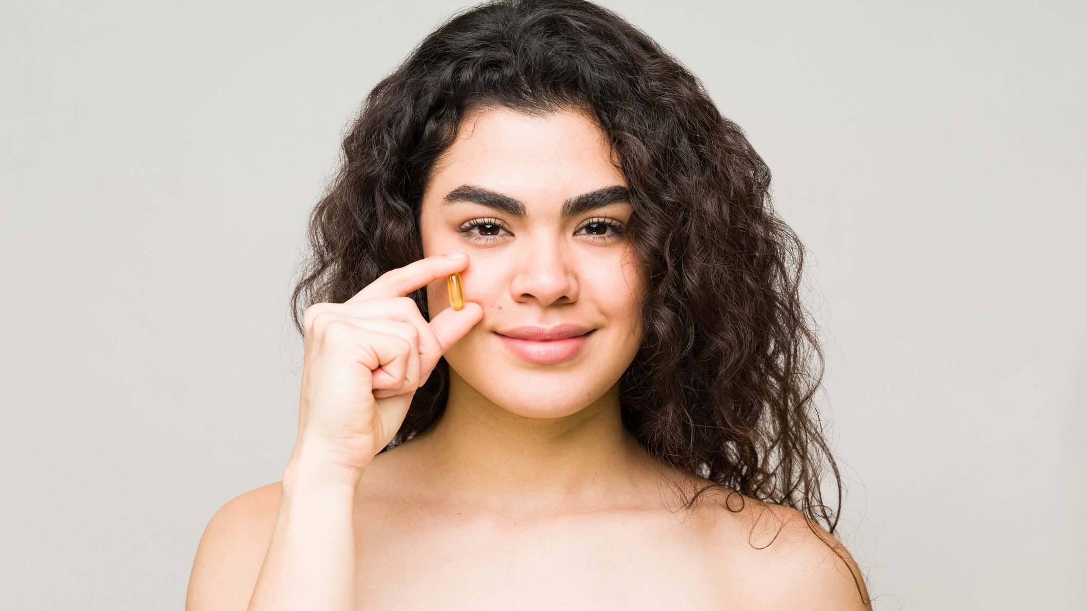 Modelo femenina sosteniendo una pastilla delante de su cara