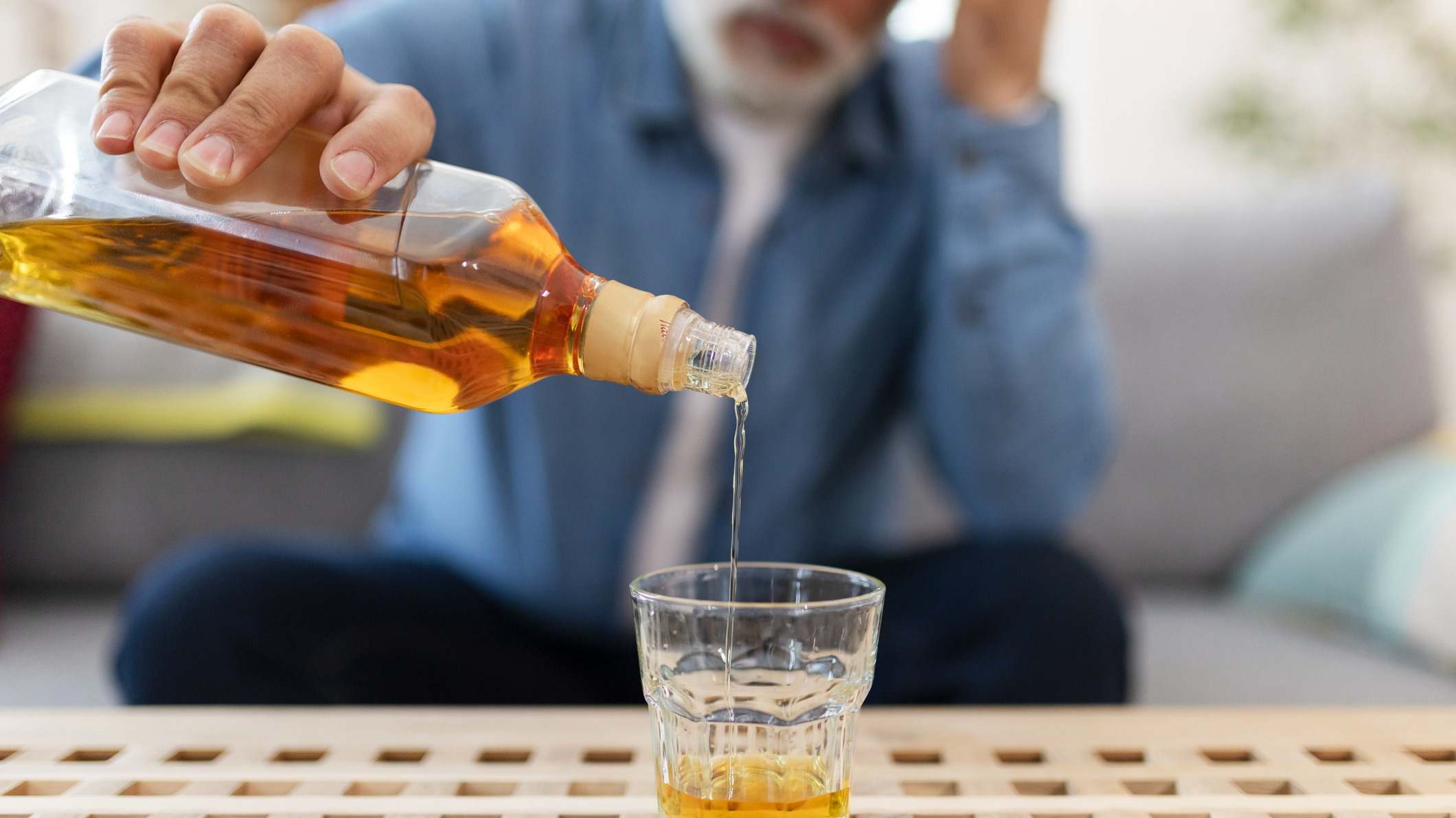 Hombre sirviéndose un vaso de whisky en su casa